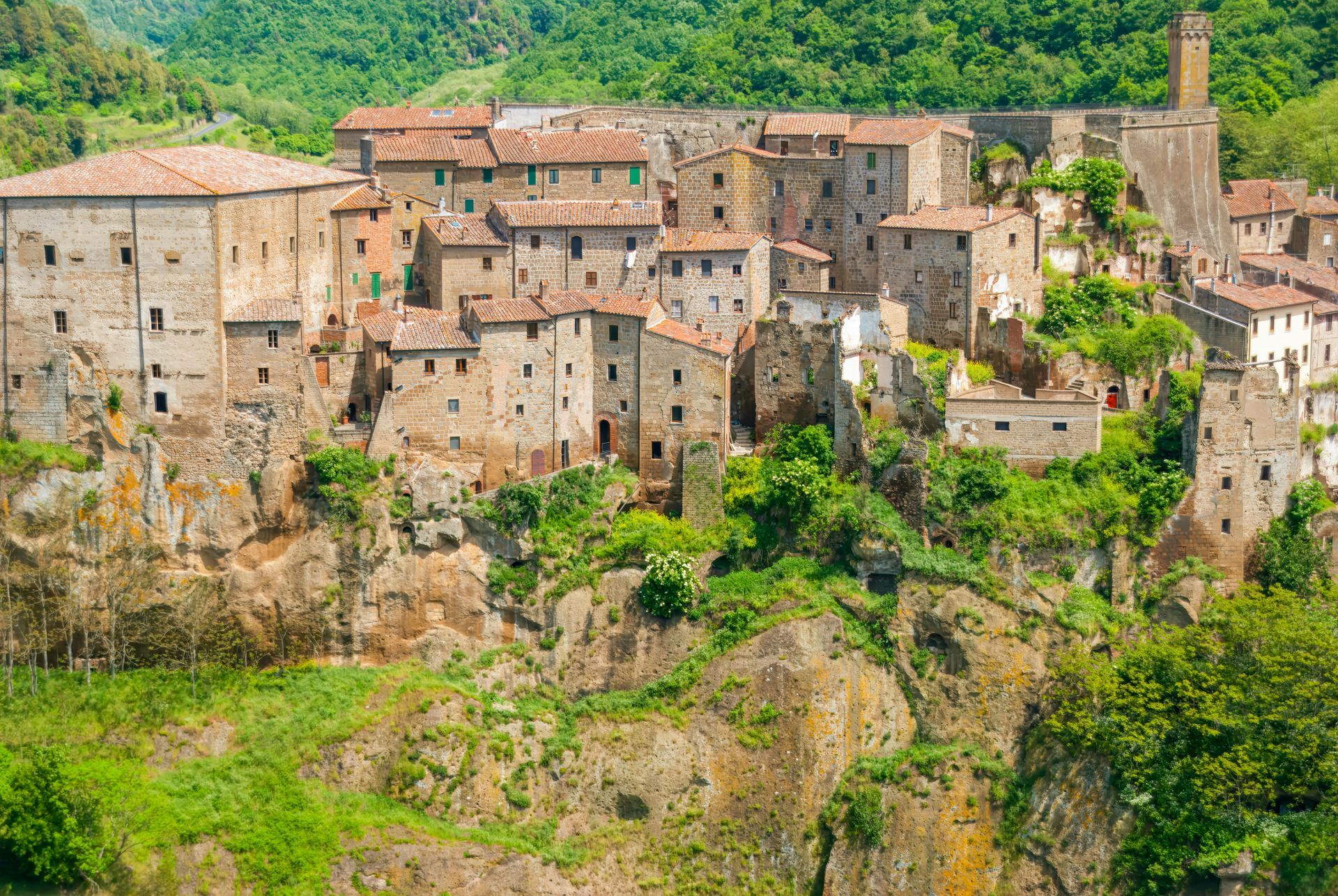 An aerial view of a small town on a cliff surrounded by trees in Tuscany, Italy.