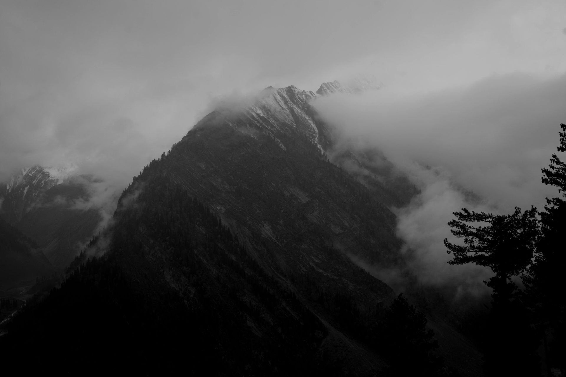 A black and white photo of a mountain covered in fog.