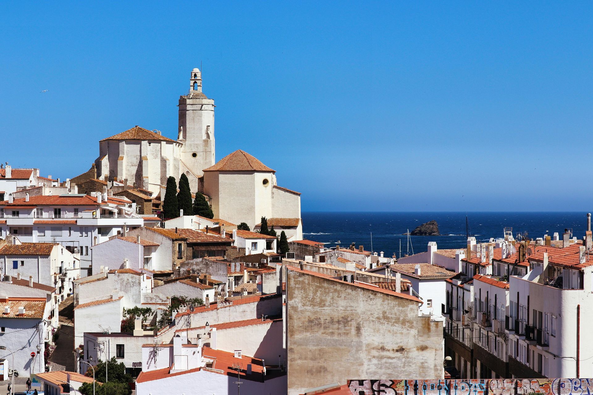 A city with a church on top of a hill overlooking the Mediterranean ocean.