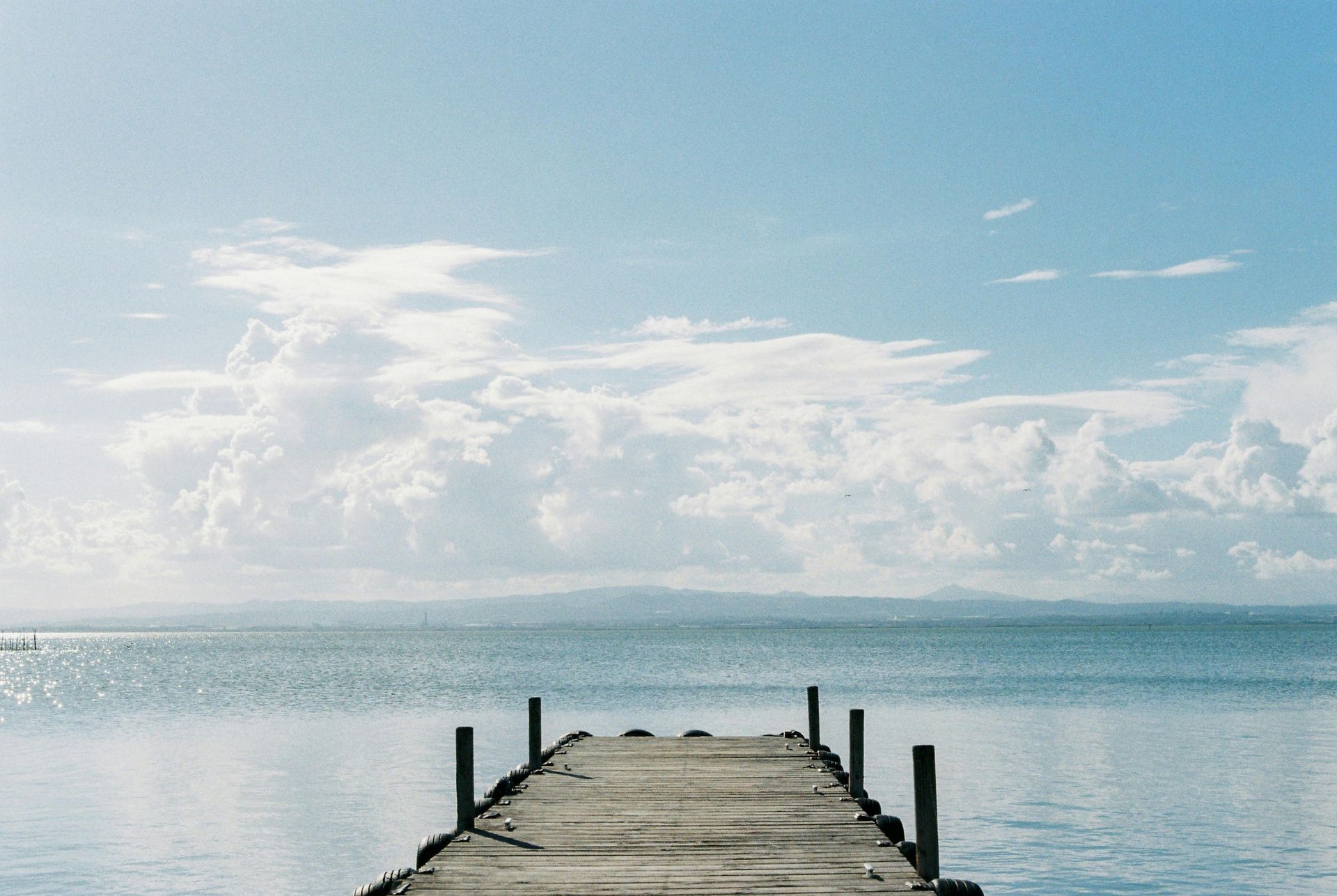 A wooden pier leading into the ocean on a sunny day.