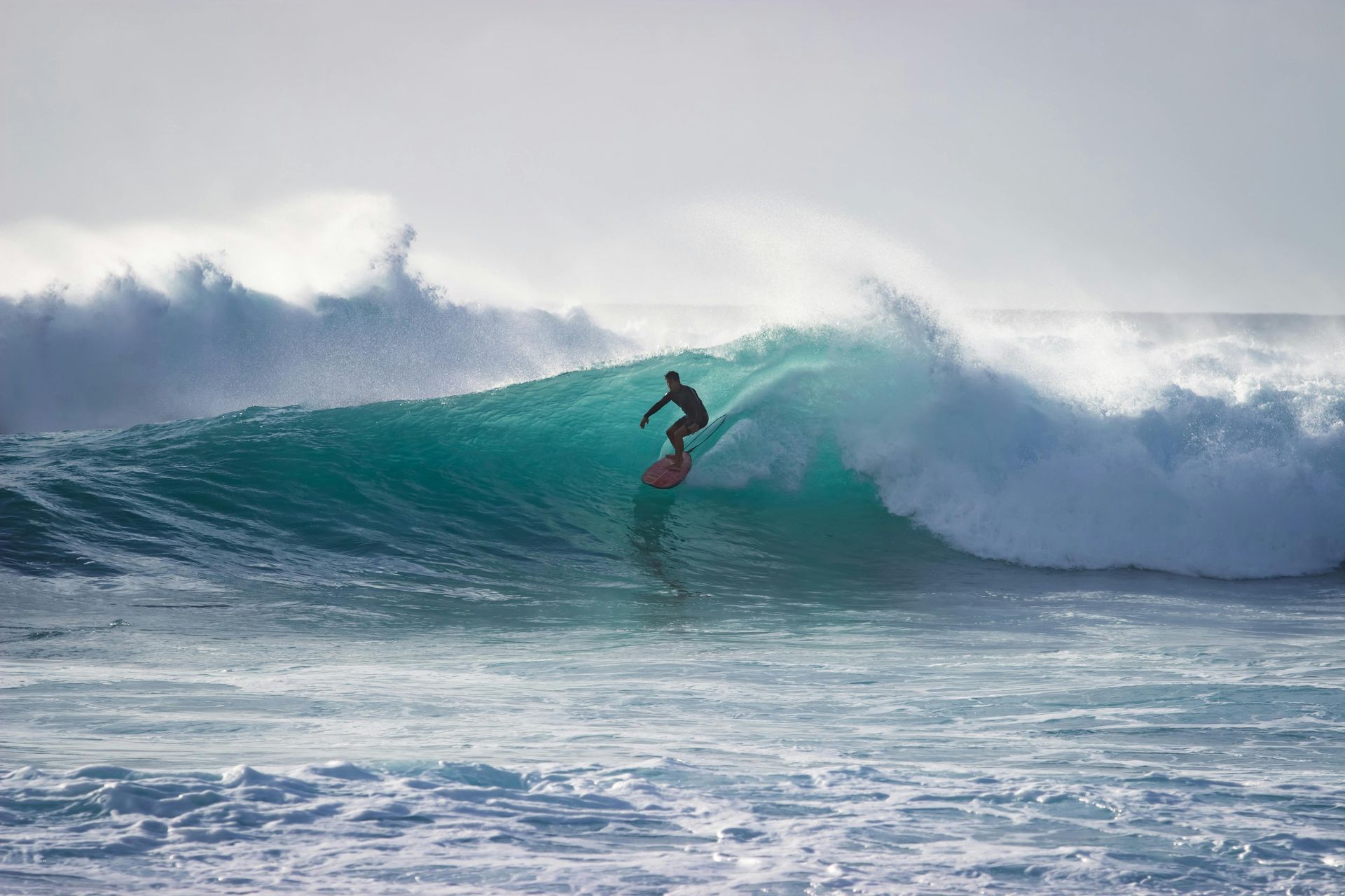 A man is riding a wave on a surfboard in the ocean.