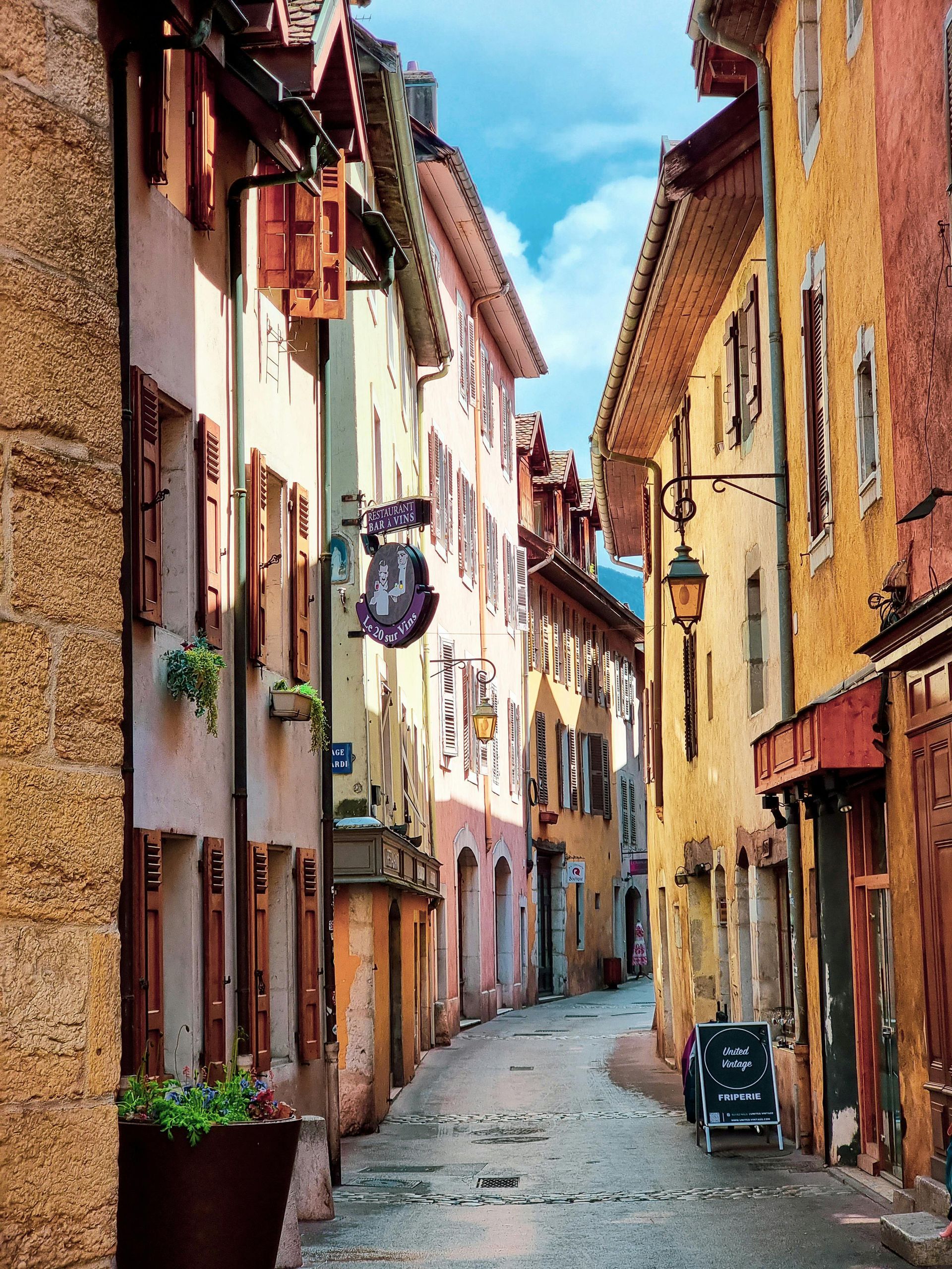 A narrow alleyway between two buildings with a sign that says ' a ' on it in Annecy, France.