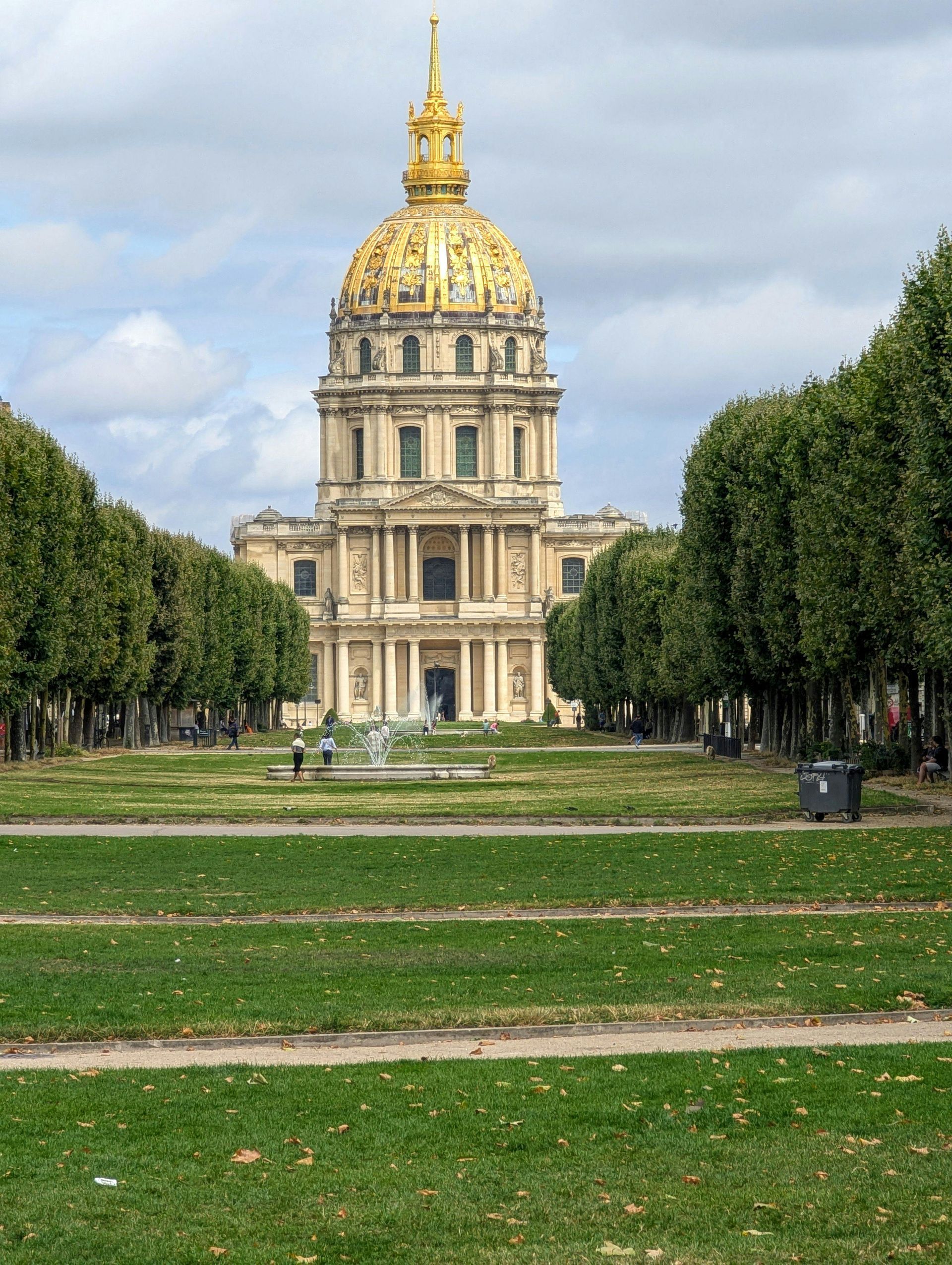 A large building with a dome on top is surrounded by trees and grass in Champagne, France.