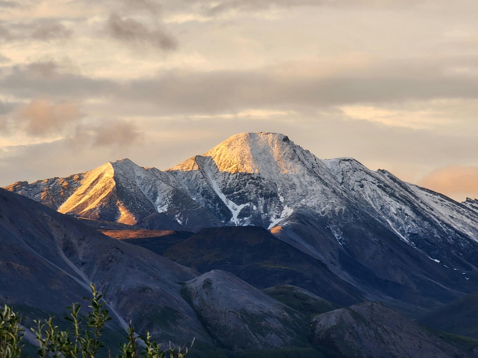 The sun is shining on the snow covered mountains in Alaska. 