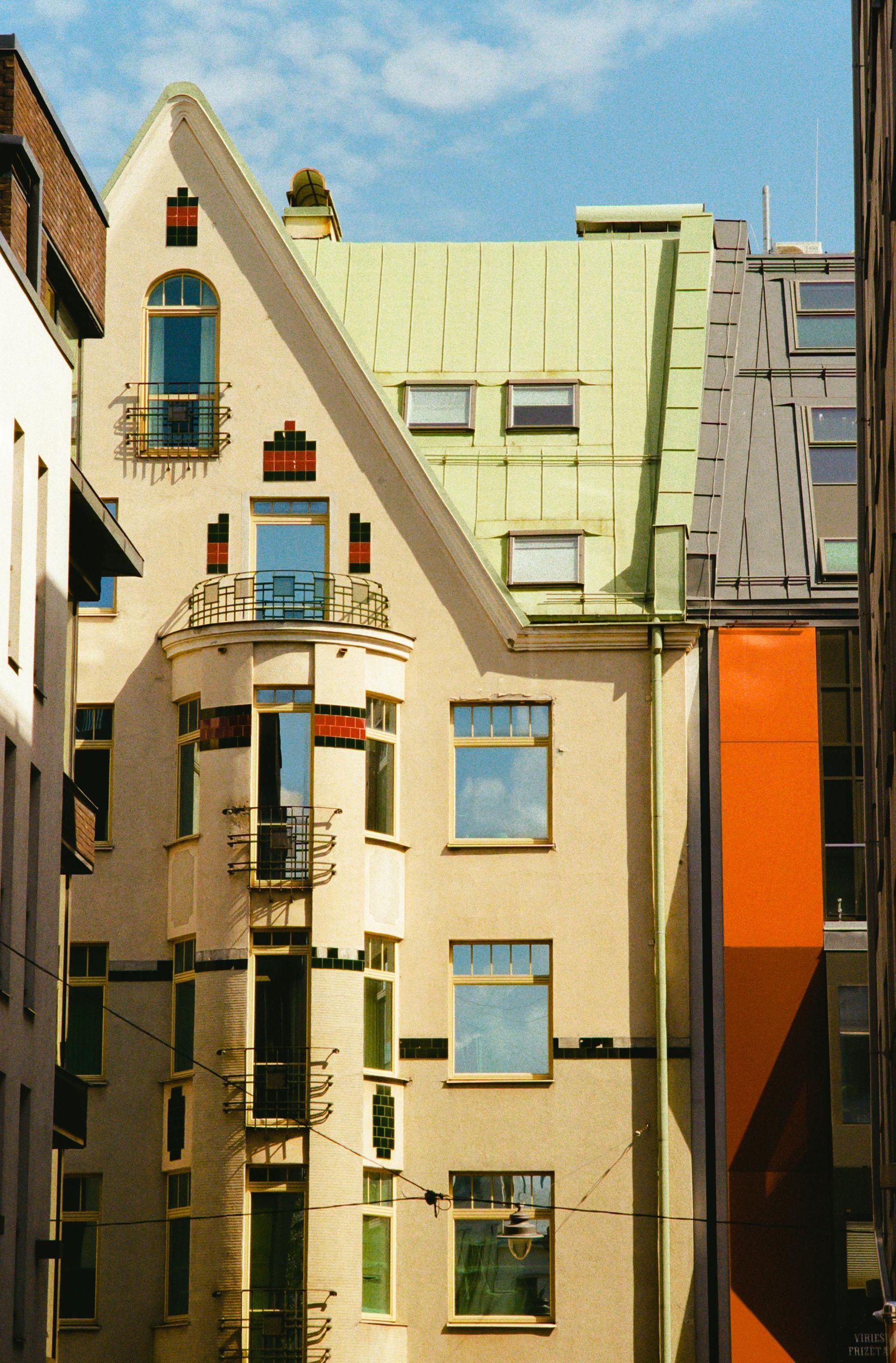 A white building with a green roof and a balcony