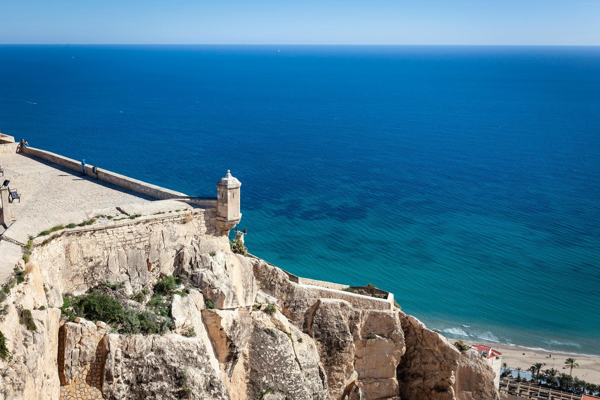 An aerial view of a castle on a cliff overlooking the Mediterranean ocean.