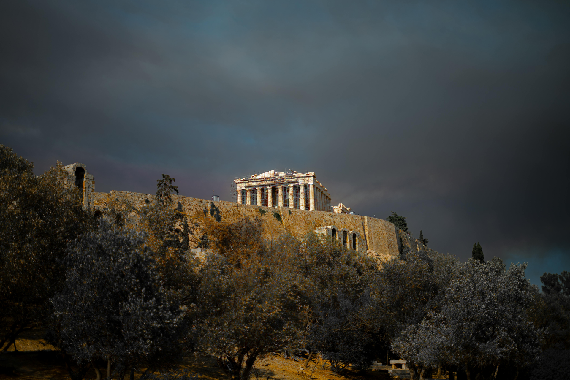 The Parthenon on top of a hill surrounded by trees on a cloudy day in Athens, Greece.