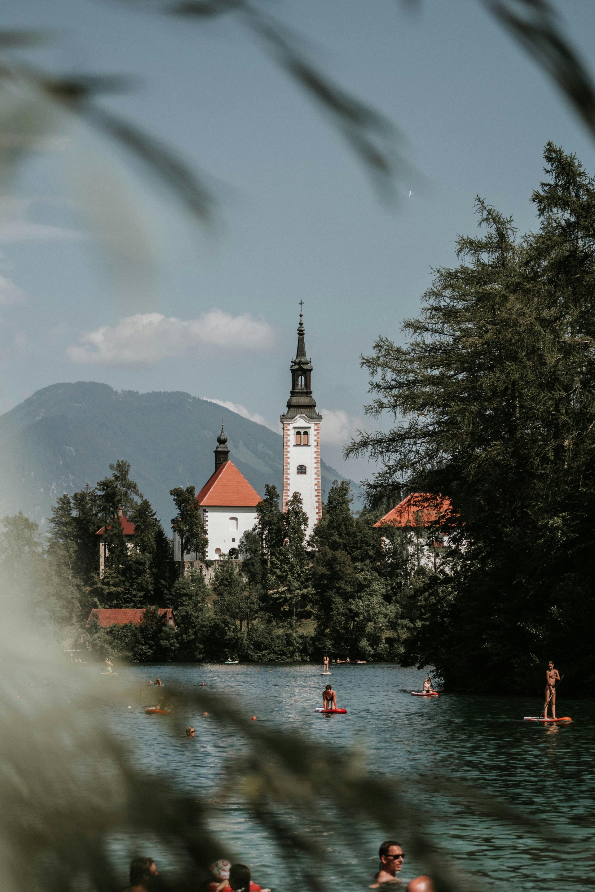 A group of people are swimming in Lake Bled with a church in the background in Slovenia. 