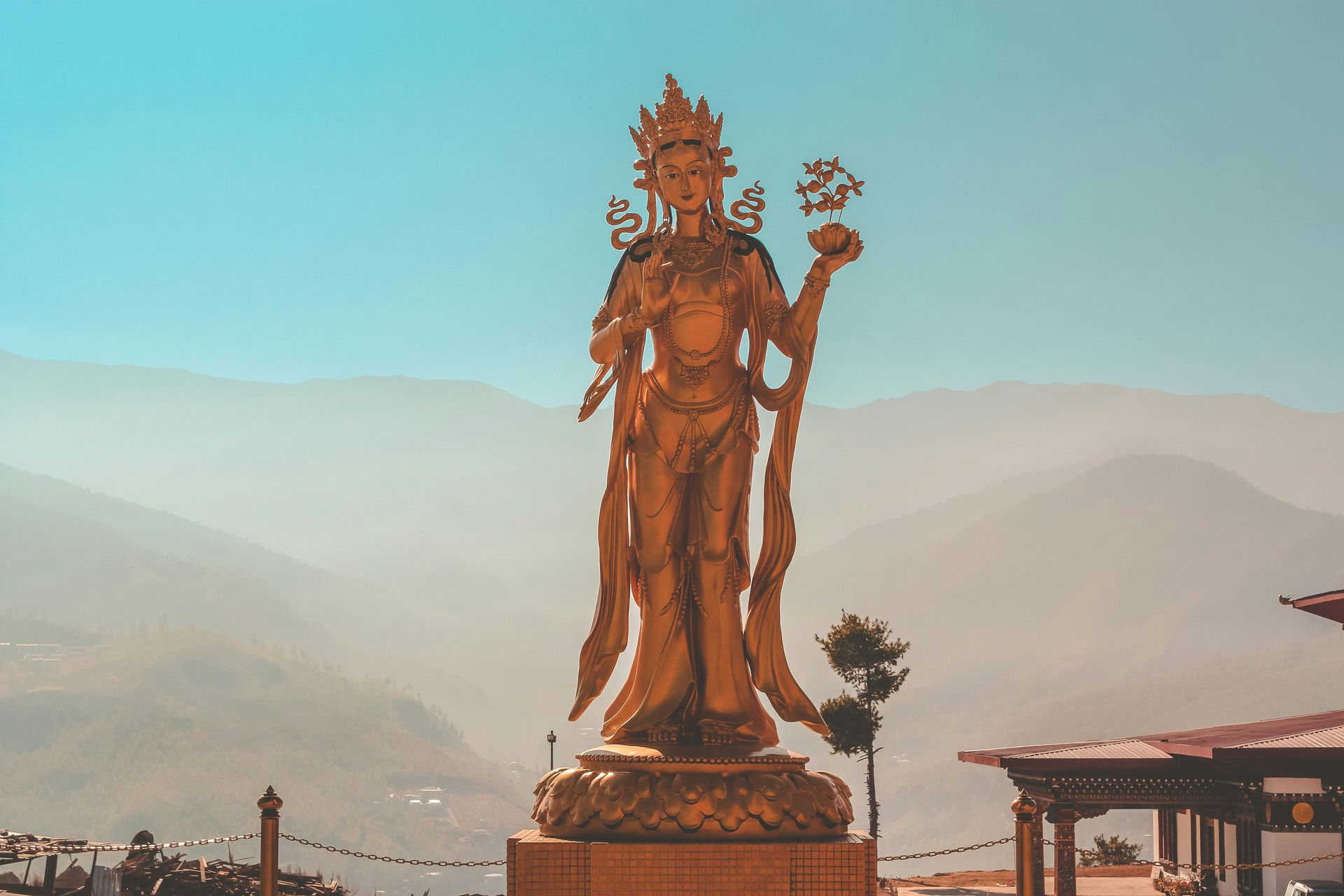 A gold female buddha statue standing in front of a mountain range in Bhutan.