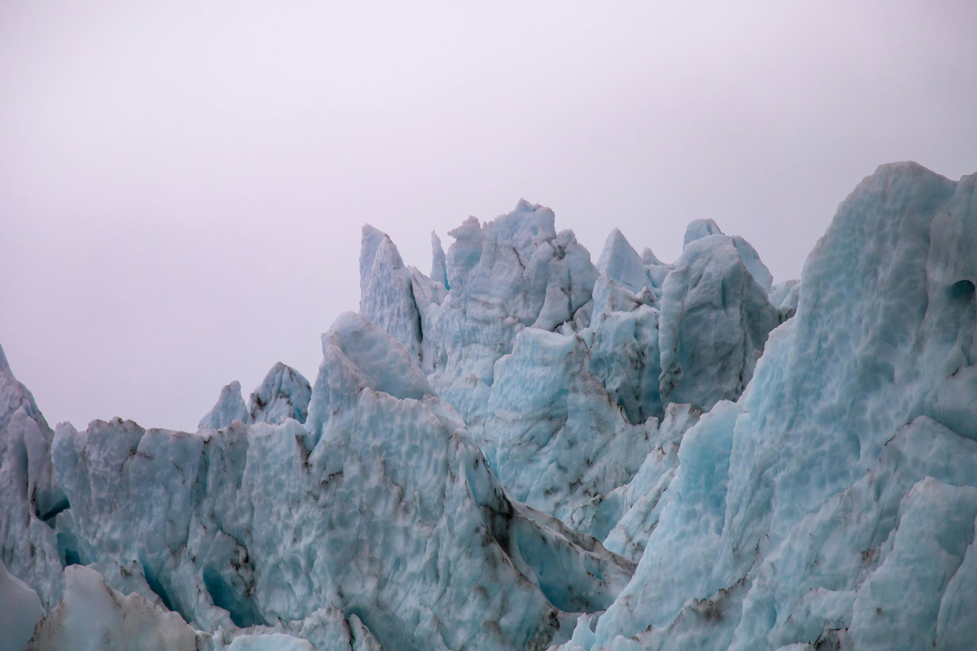 A close up of a glacier covered in ice against a cloudy sky in Antarctica.