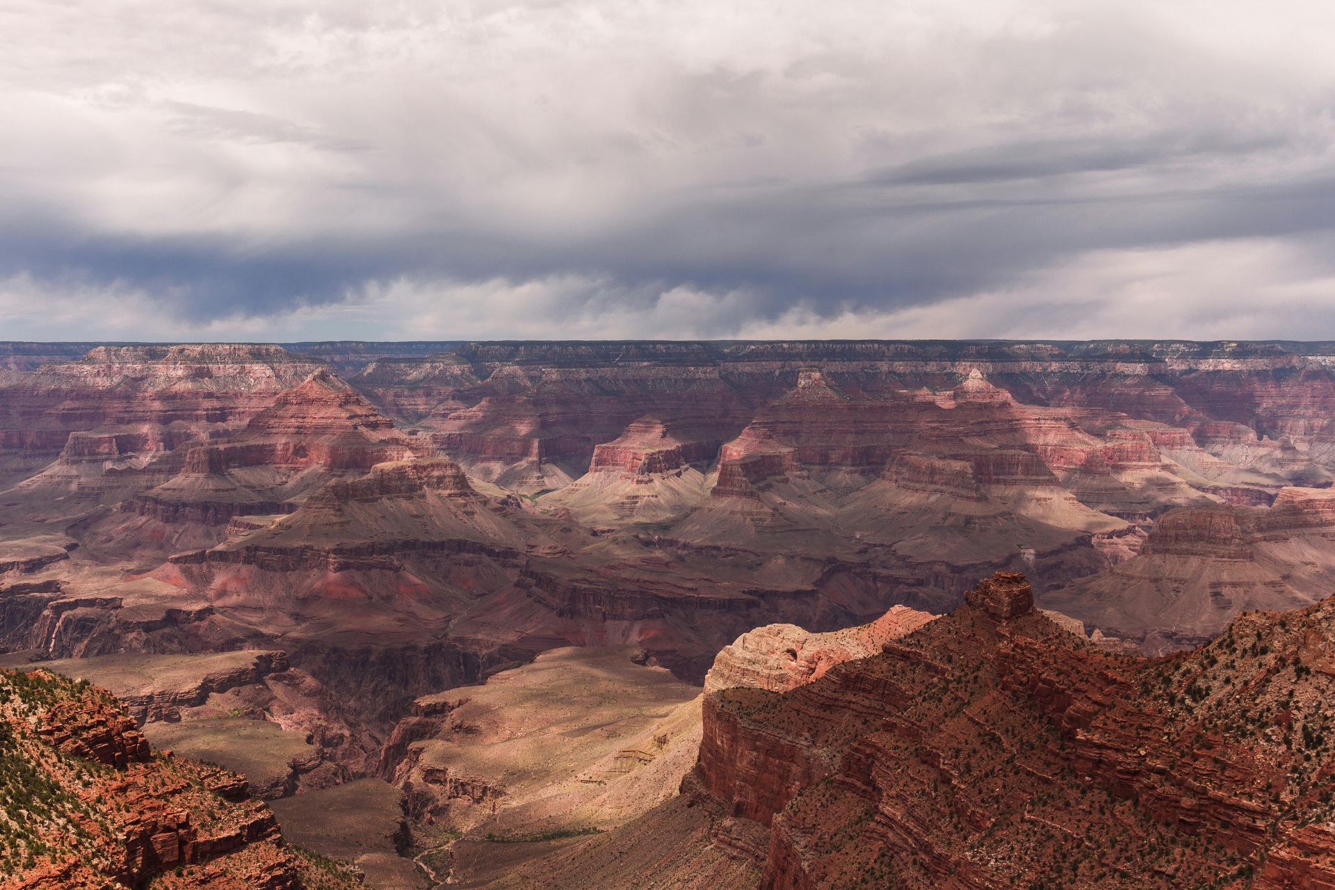 A view of the Grand Canyon from a cliff on a cloudy day in Arizona.