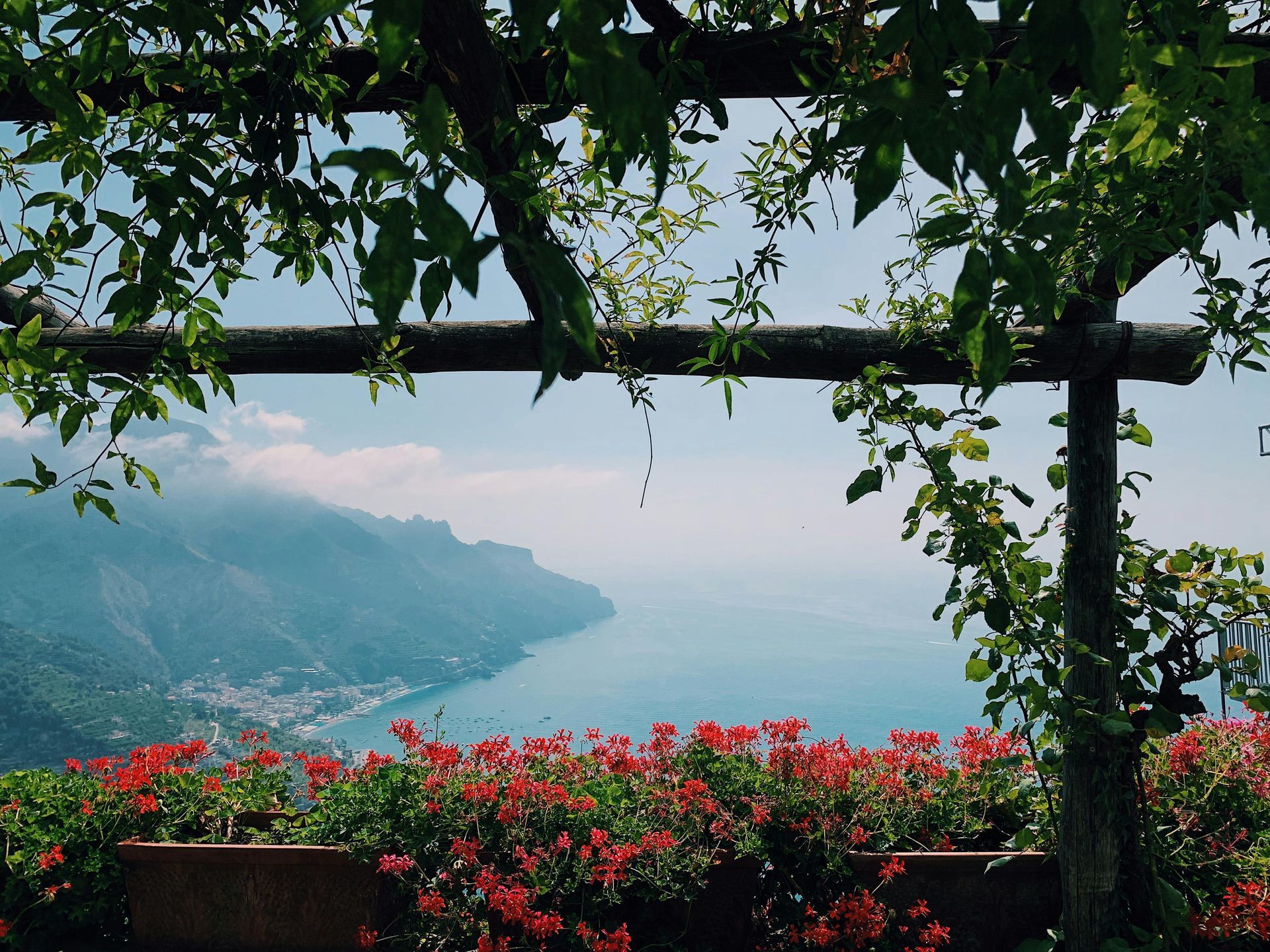 A view of a lake through a pergola with red flowers on the Amalfi Coast.