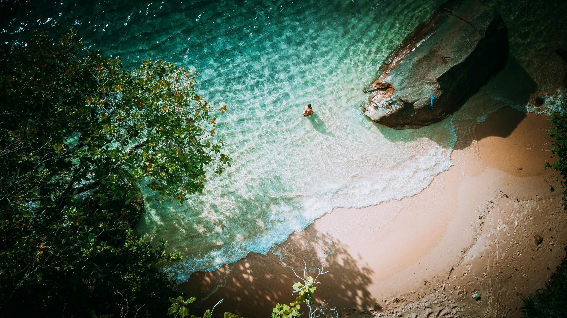 An aerial view of a beach with a boat in the water on Seychelles Island.