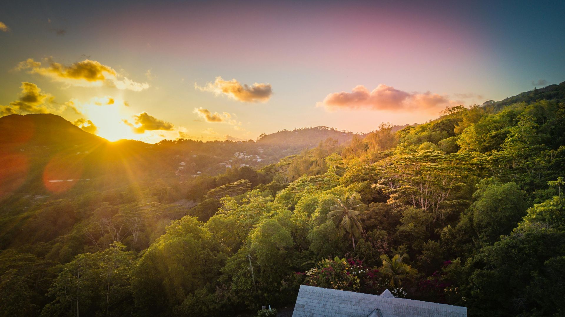 An aerial view of a sunset over a lush green forest on Seychelles Island.