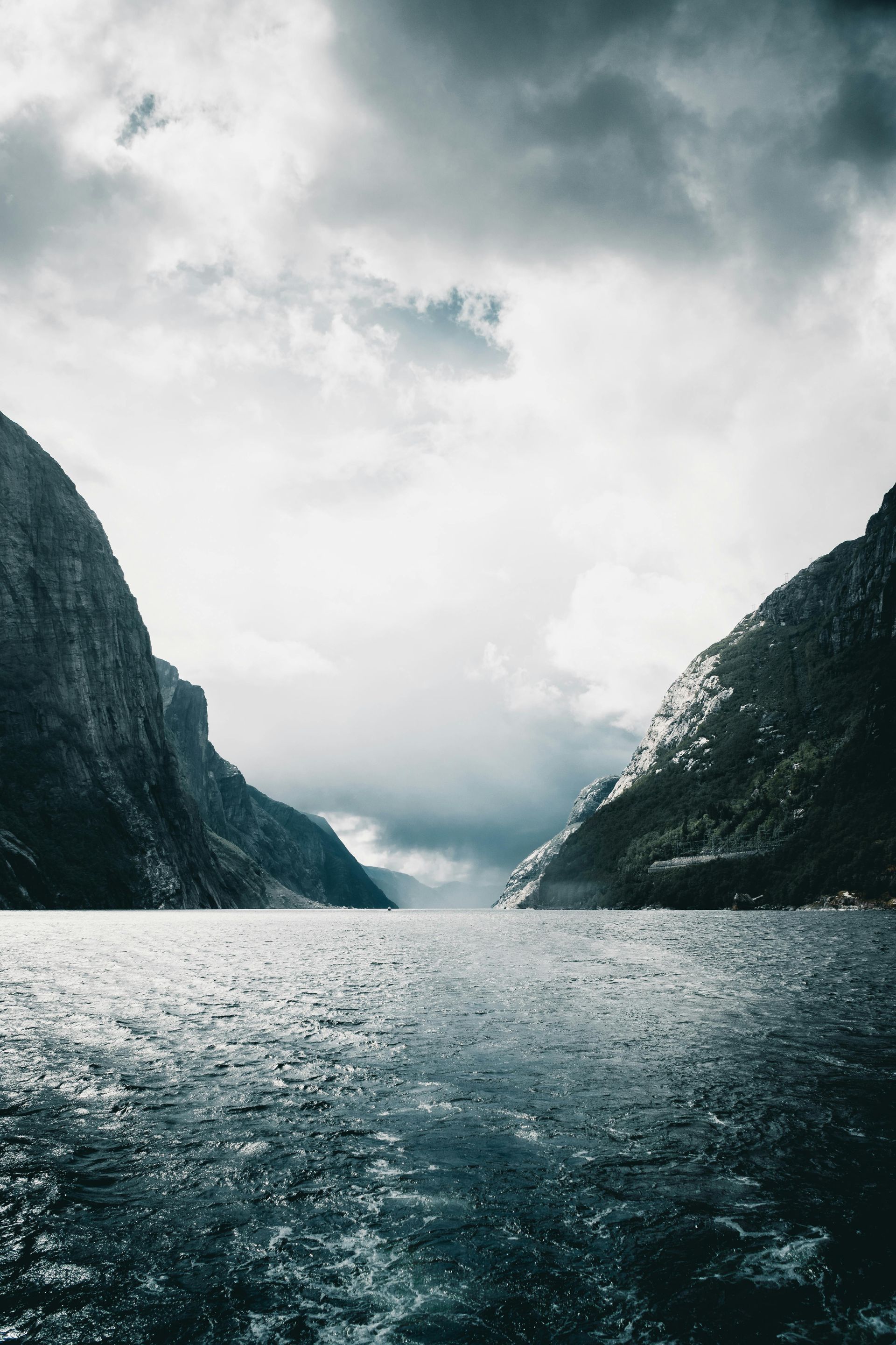 A large body of water surrounded by mountains on a cloudy day on the Norwegian Coast.