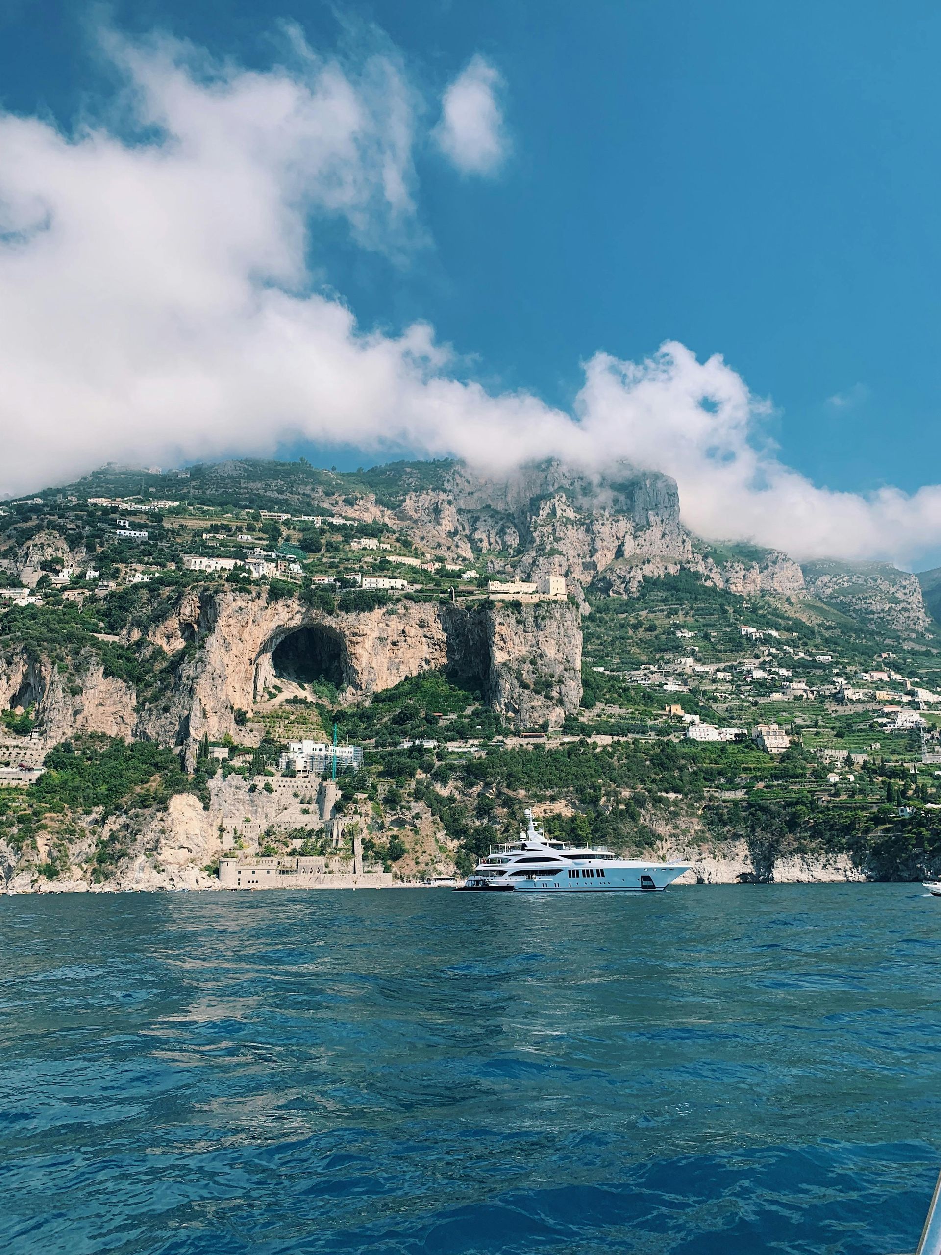 A boat is floating on top of a body of water with a mountain in the background in the Amalfi Coast, Italy.