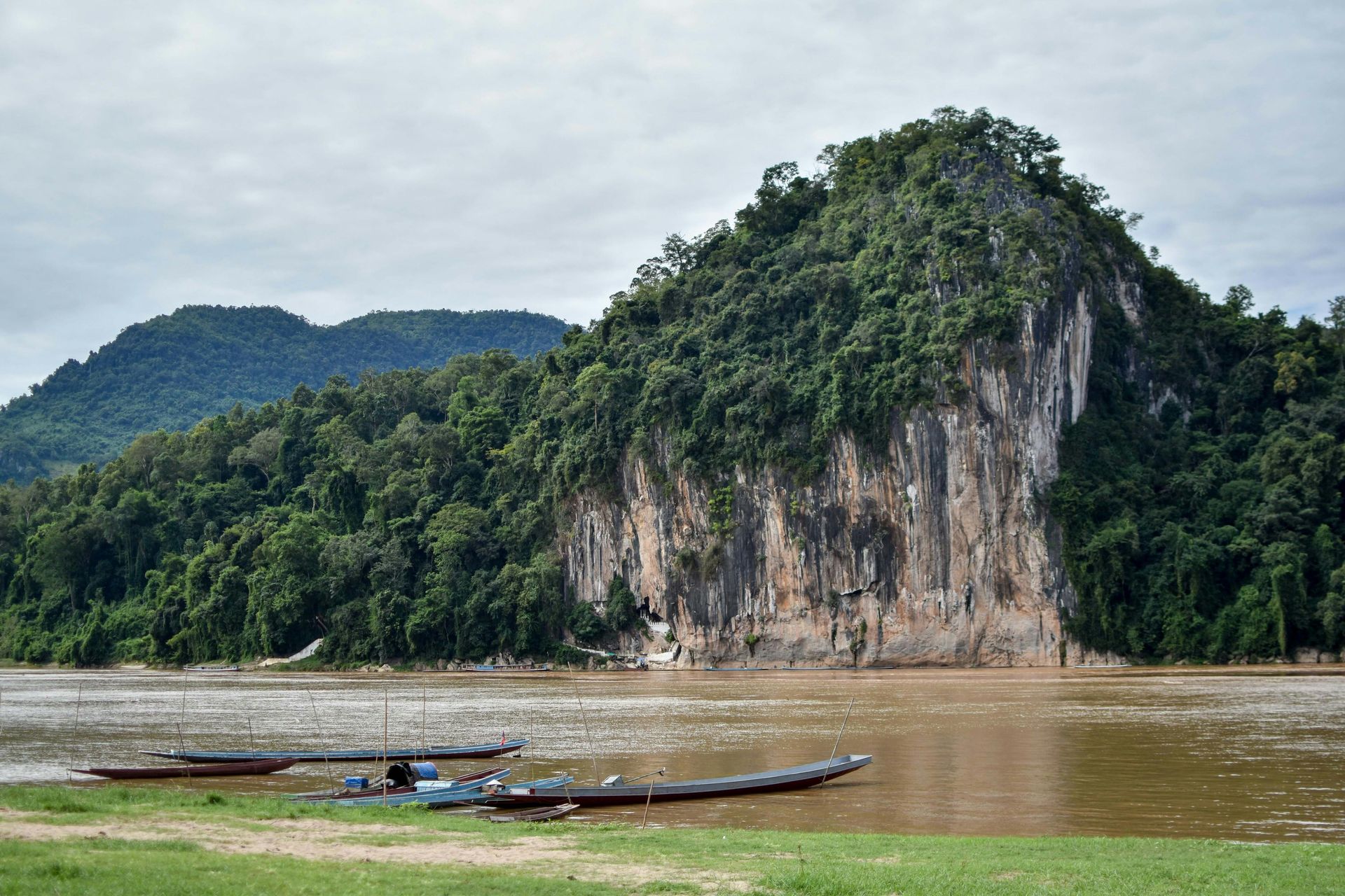 A river with a mountain in the background and boats in the foreground in Laos.