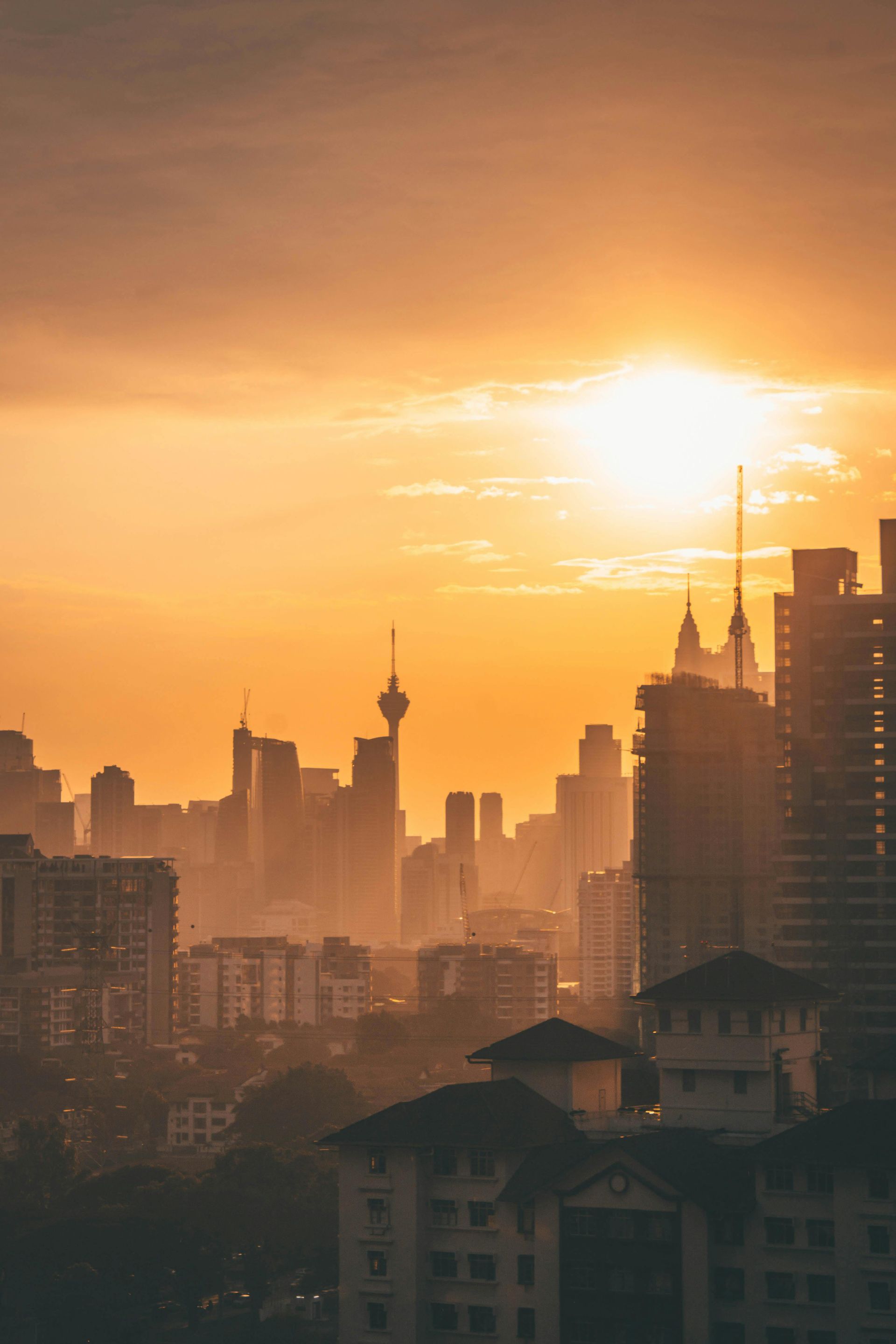 A city skyline at sunset with the sun shining through the clouds in Malaysia.