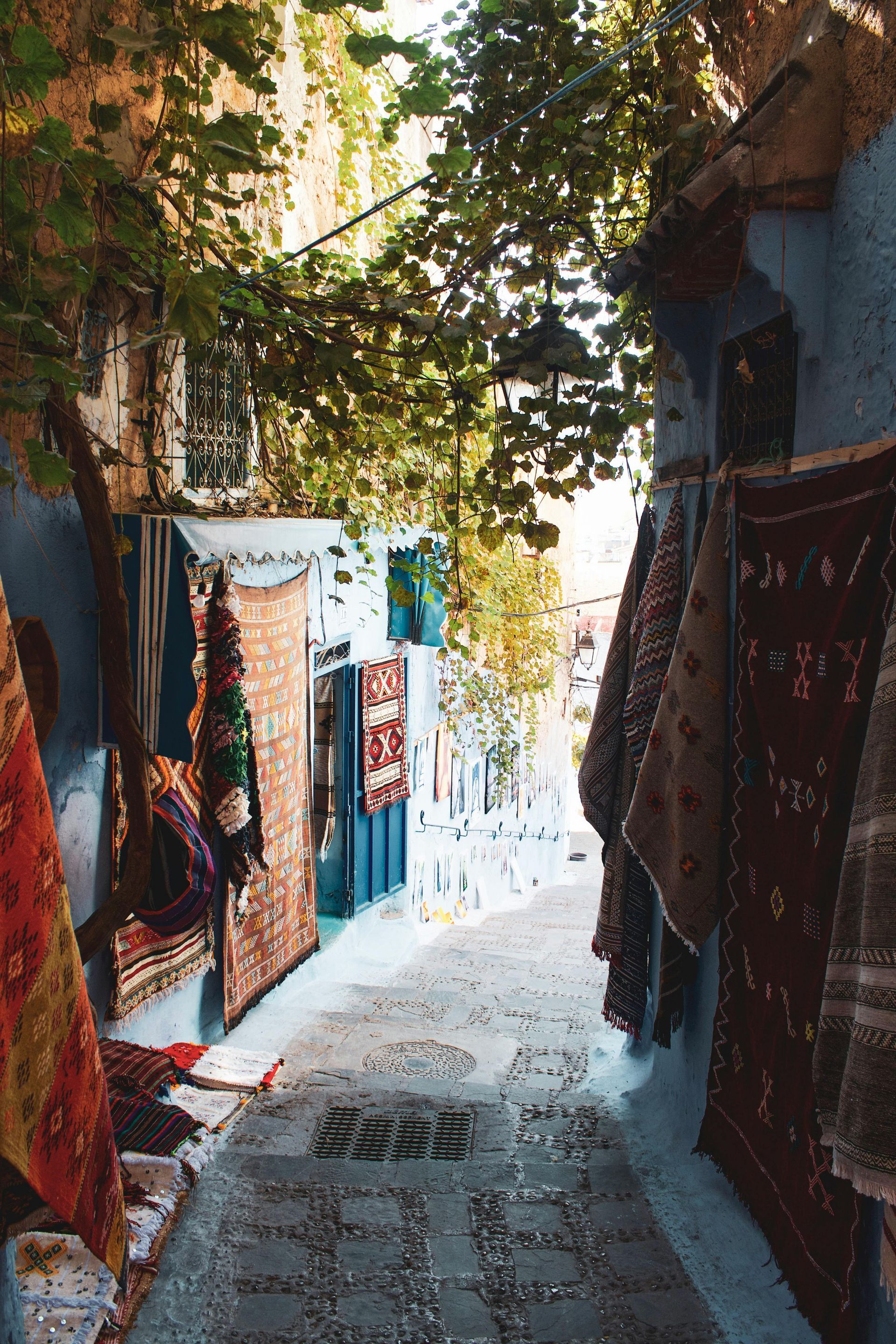 A narrow alleyway filled with lots of rugs and clothes in Morocco.