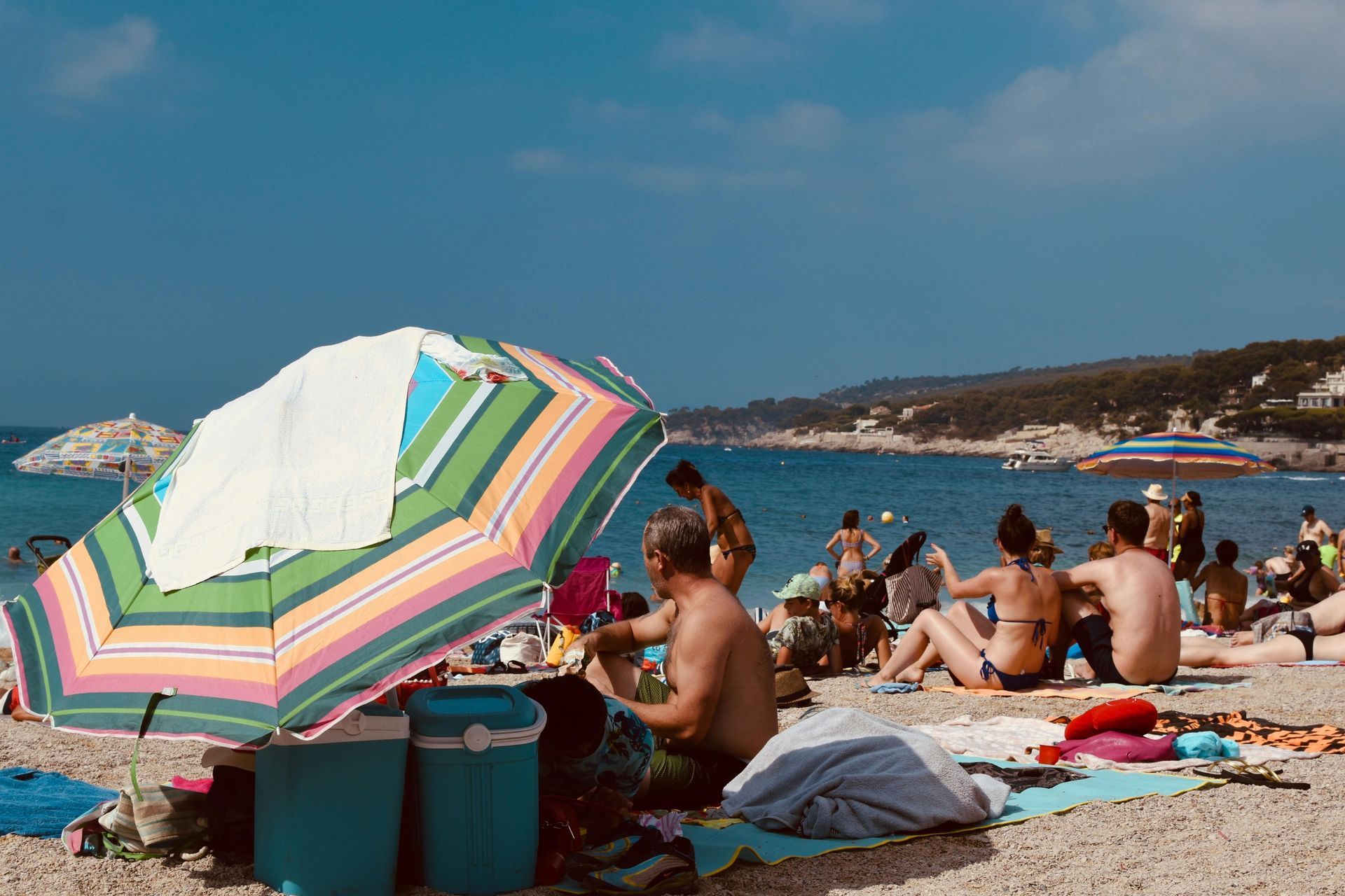 A group of people are sitting on a beach under an umbrella in Côte d’Azur.