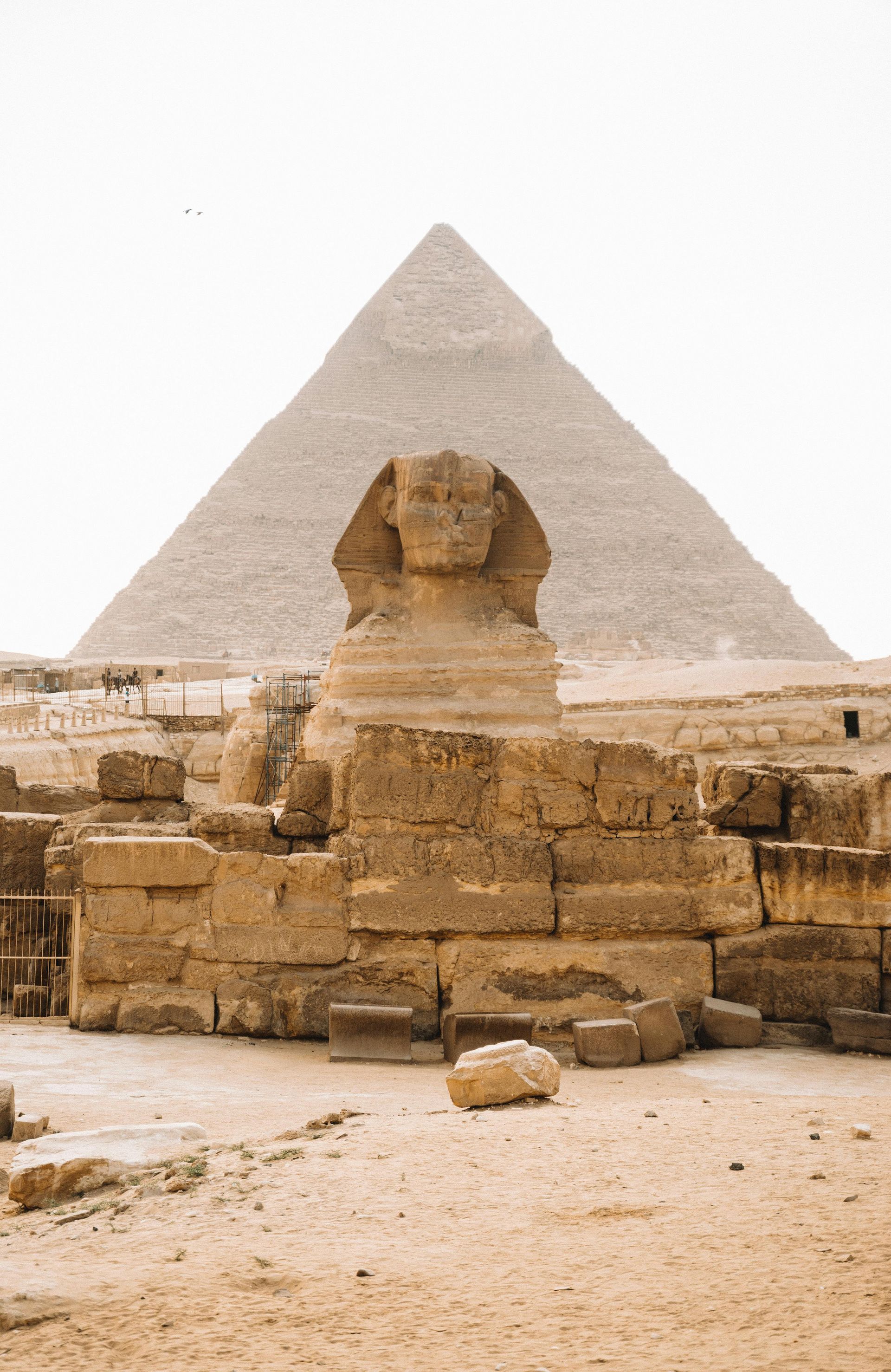 A statue of a sphinx in front of a pyramid in Egypt.