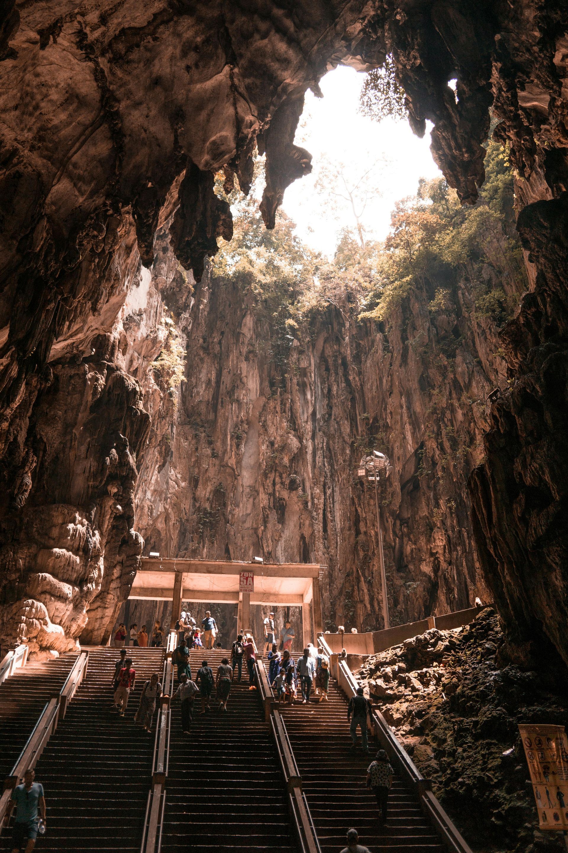 A group of people are walking up stairs in a cave in Malaysia.