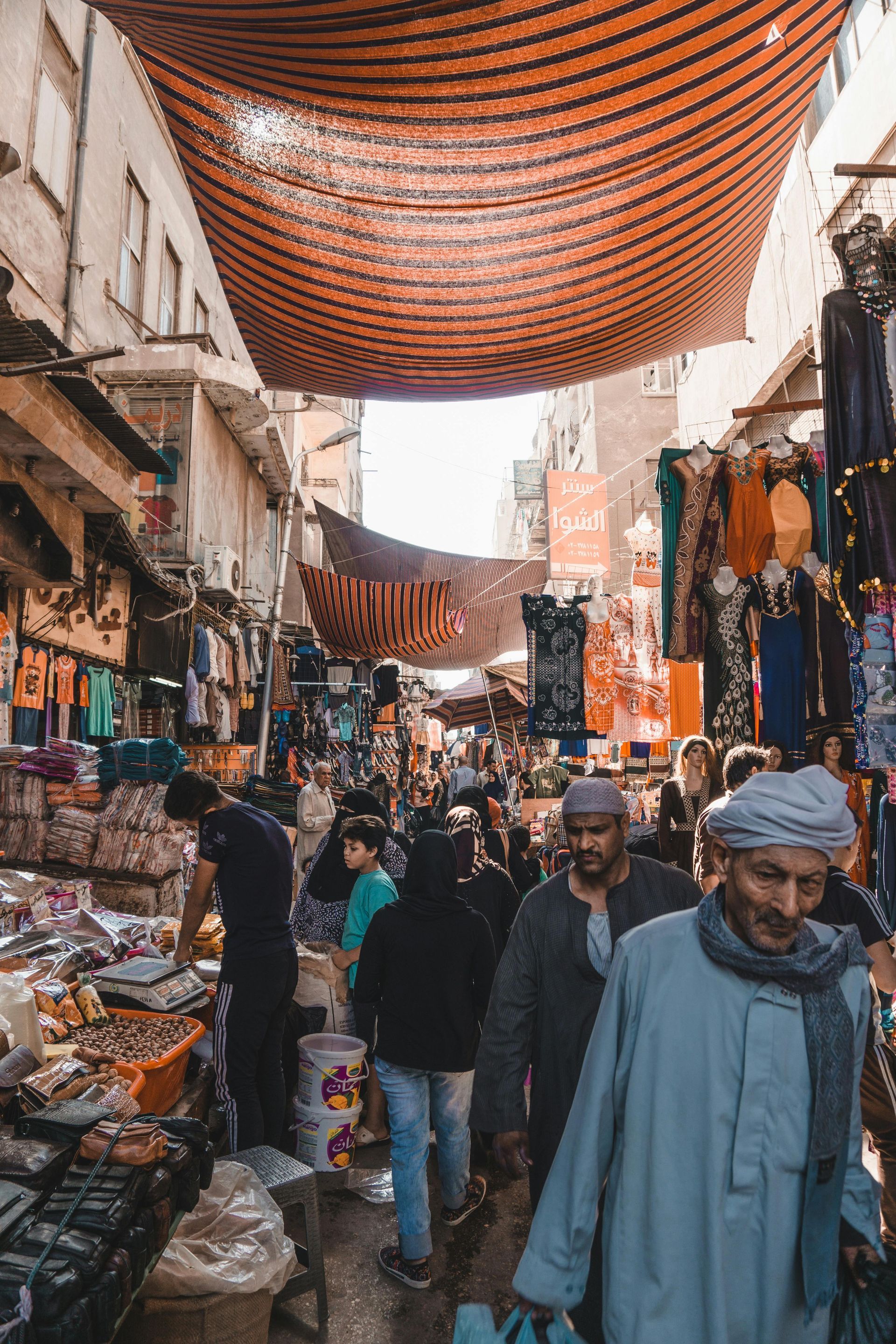 A group of people are walking down a narrow street in a market in Egypt.