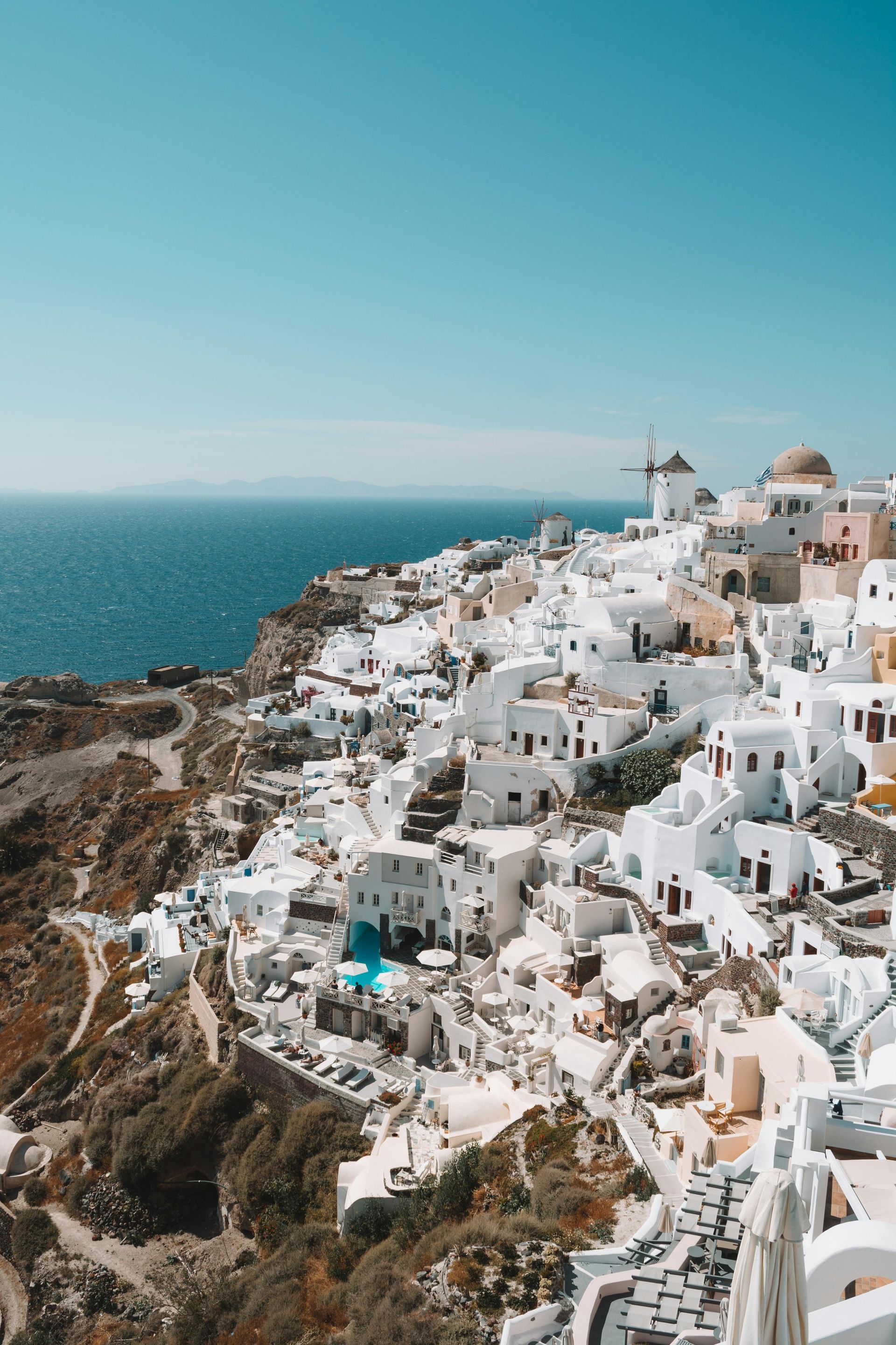 An aerial view of a small town on a hill overlooking the ocean in Santorini, Greece.