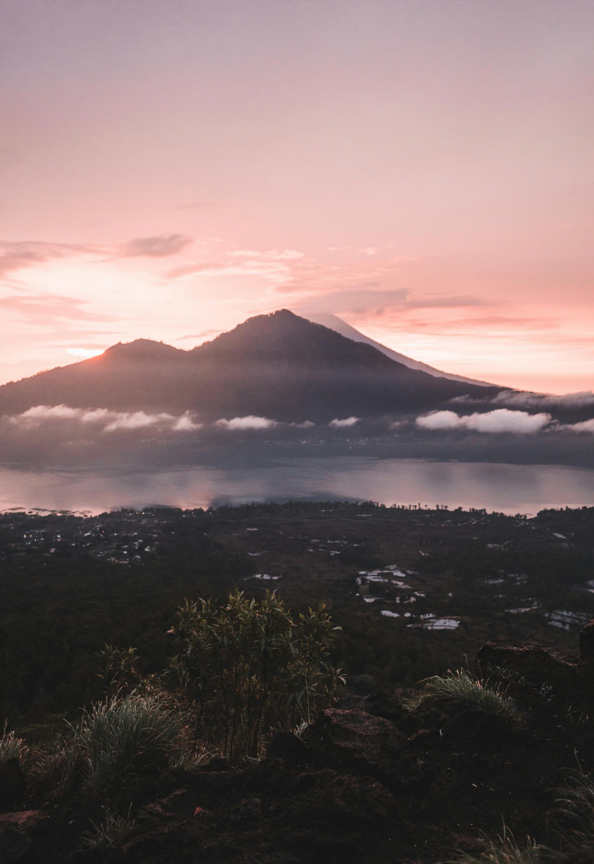 A view of a mountain at sunset with a lake in the foreground in Indonesia.