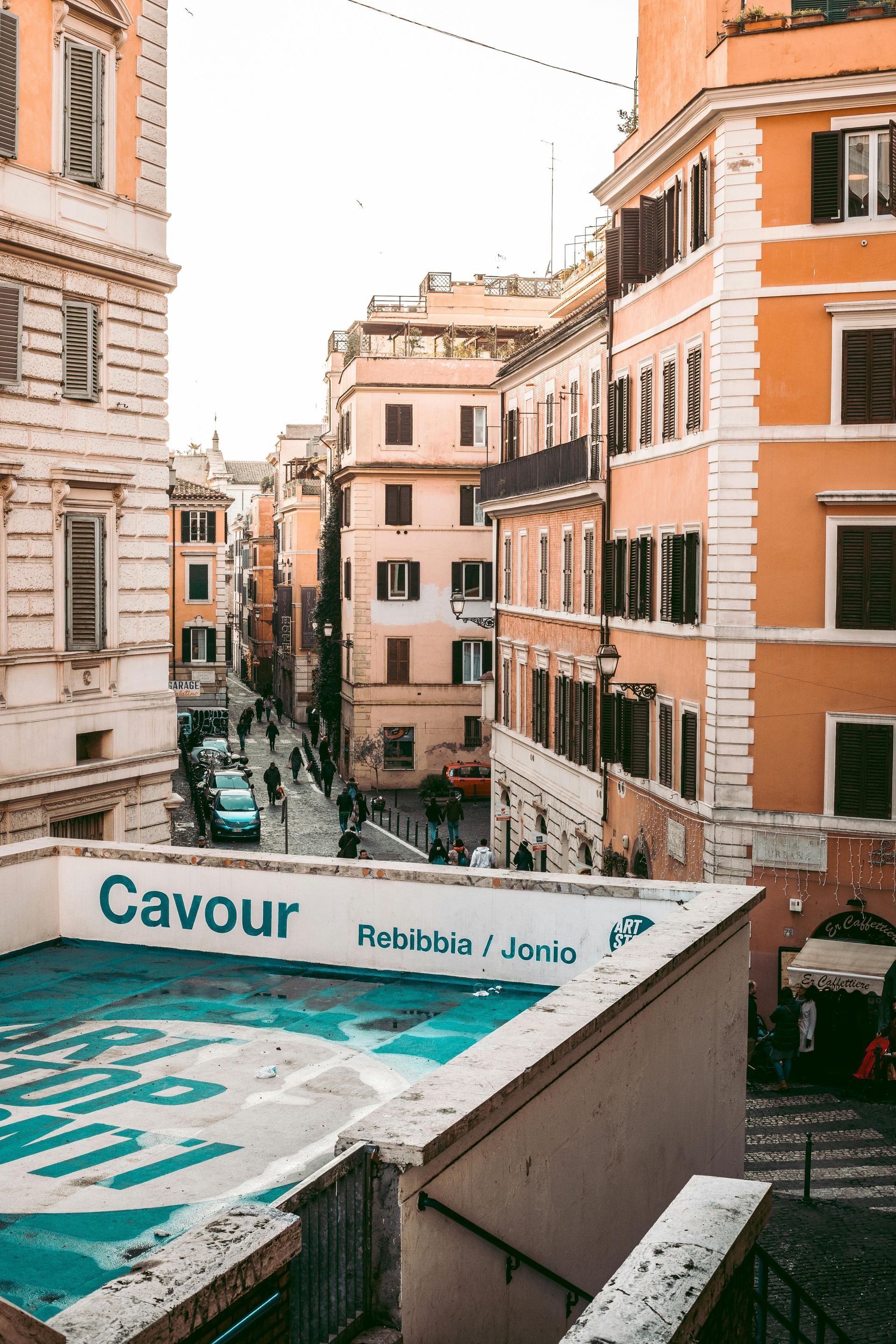 A view of a city street from a balcony with a sign that says cavour on it in Rome, Italy.