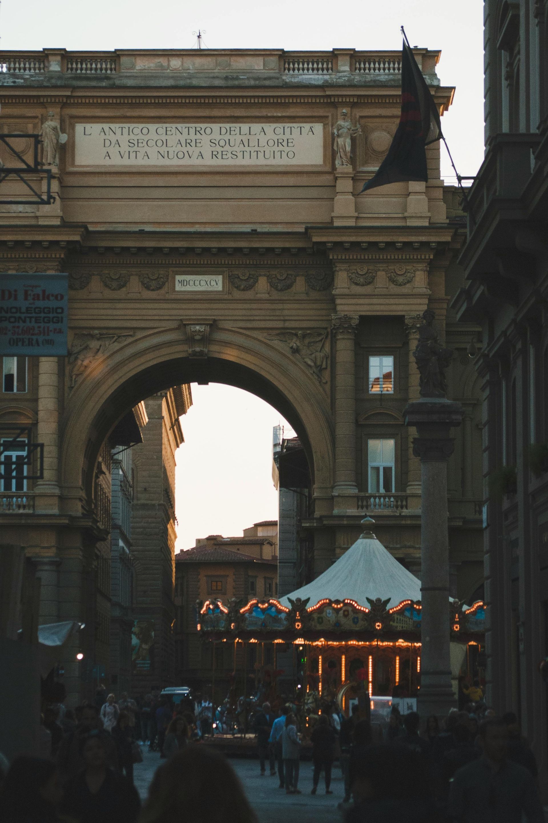 A black flag is flying in front of a large archway in Florence, Italy.