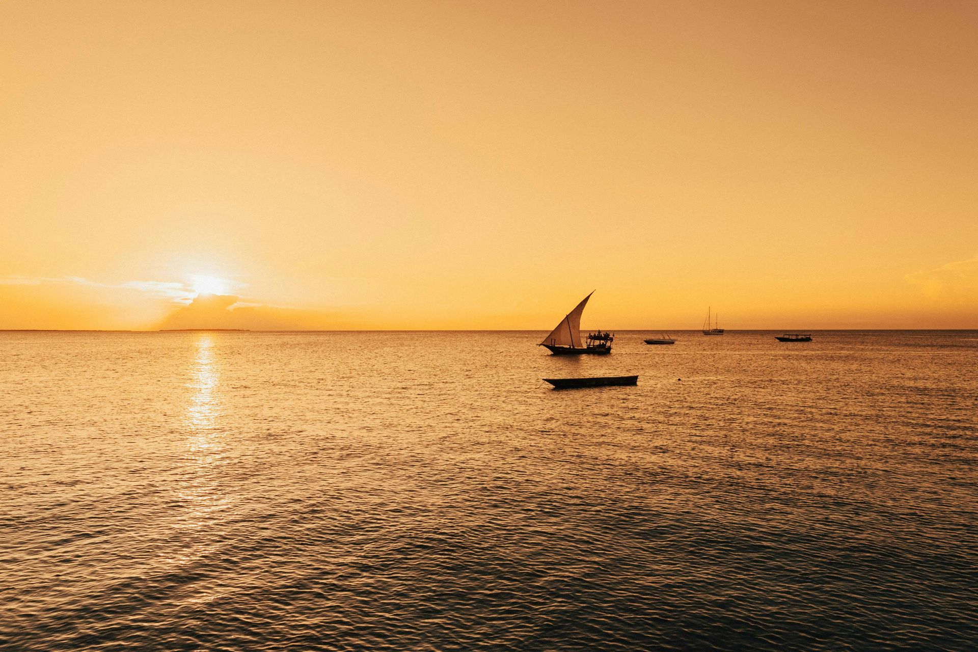 There are many boats in the ocean at sunset in Tanzania, Africa.