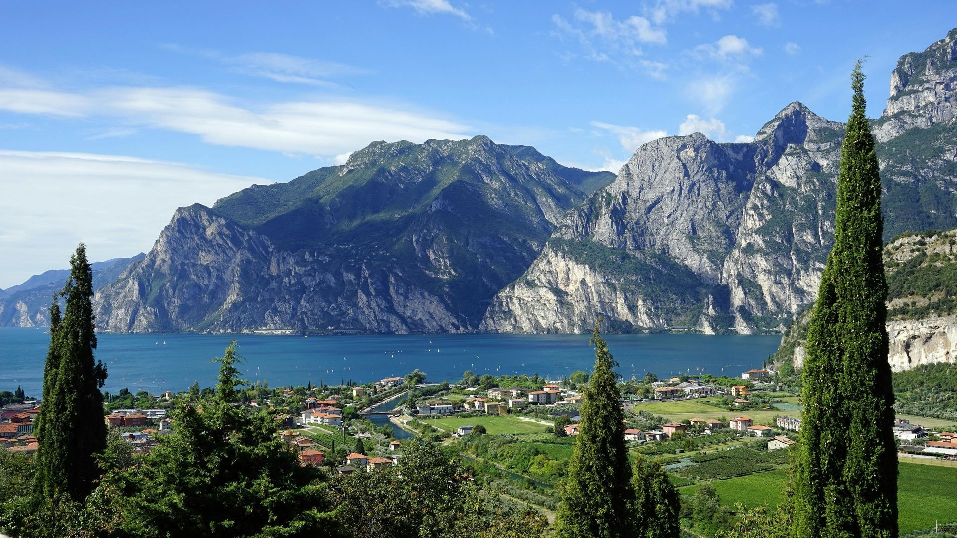 Lake Garda with mountains in the background and trees in the foreground in Italy.