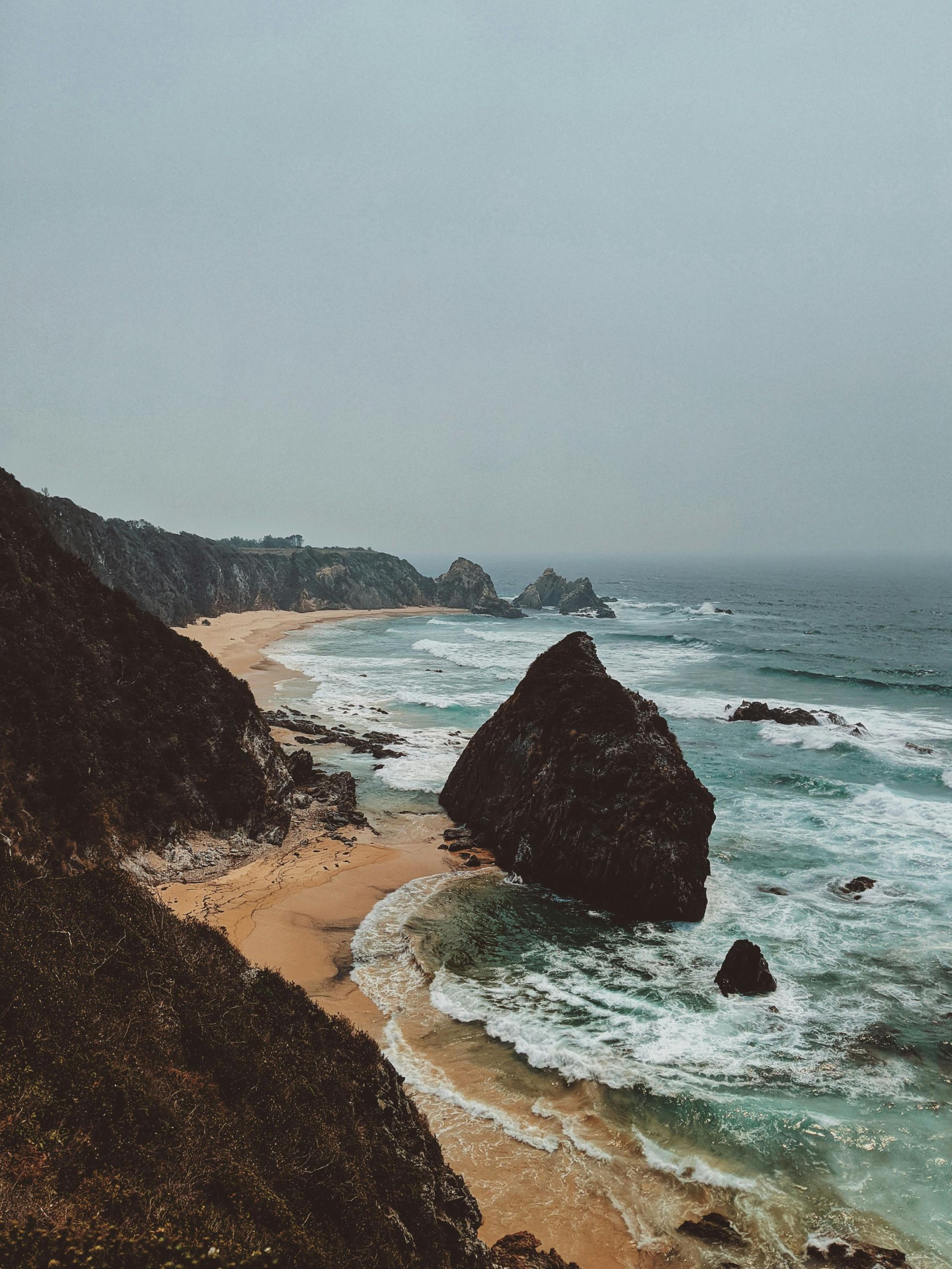 A beach with a large rock in the middle of it in Australia.