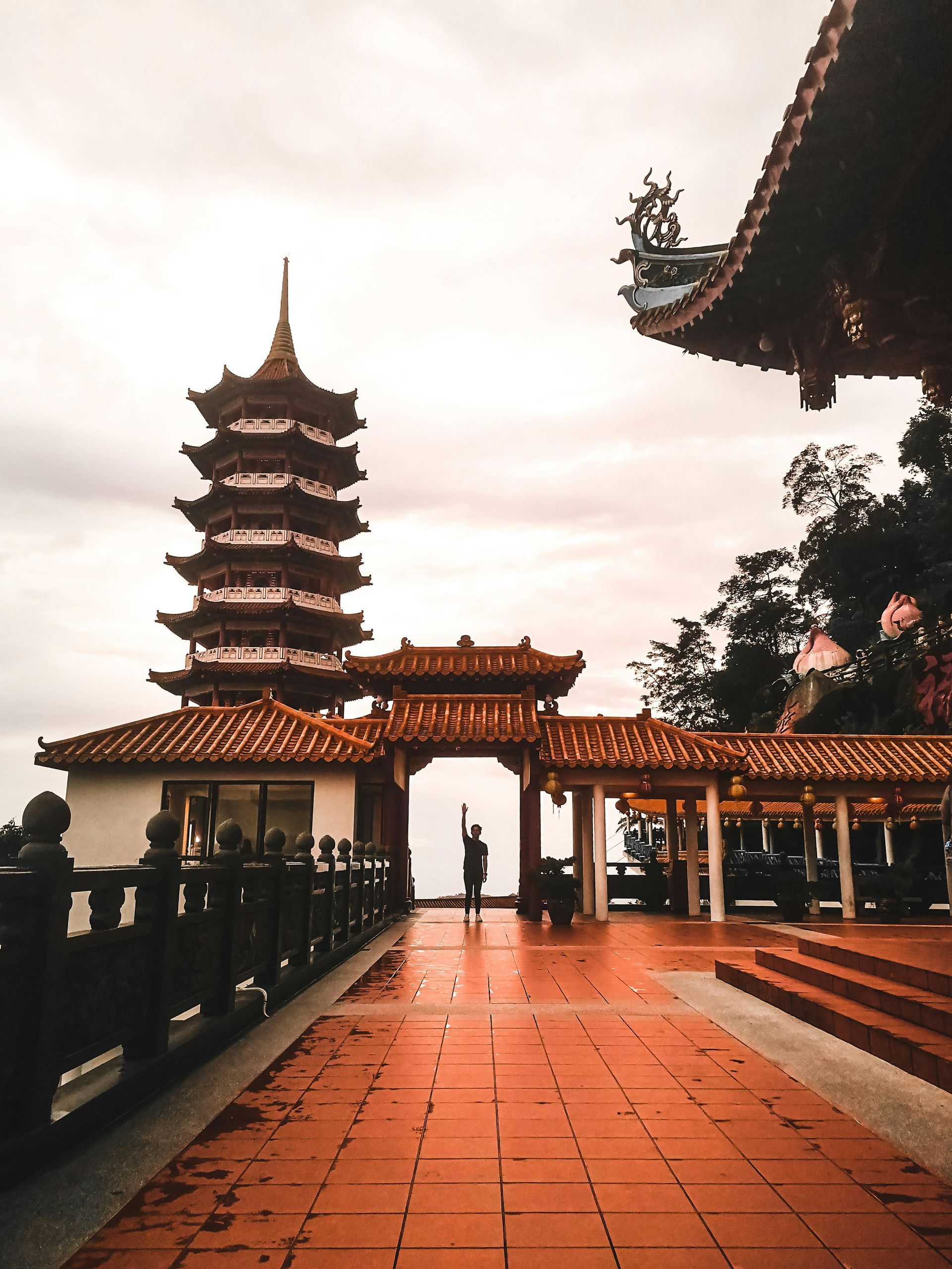 A chinese temple with a very tall tower in the background in Malaysia.