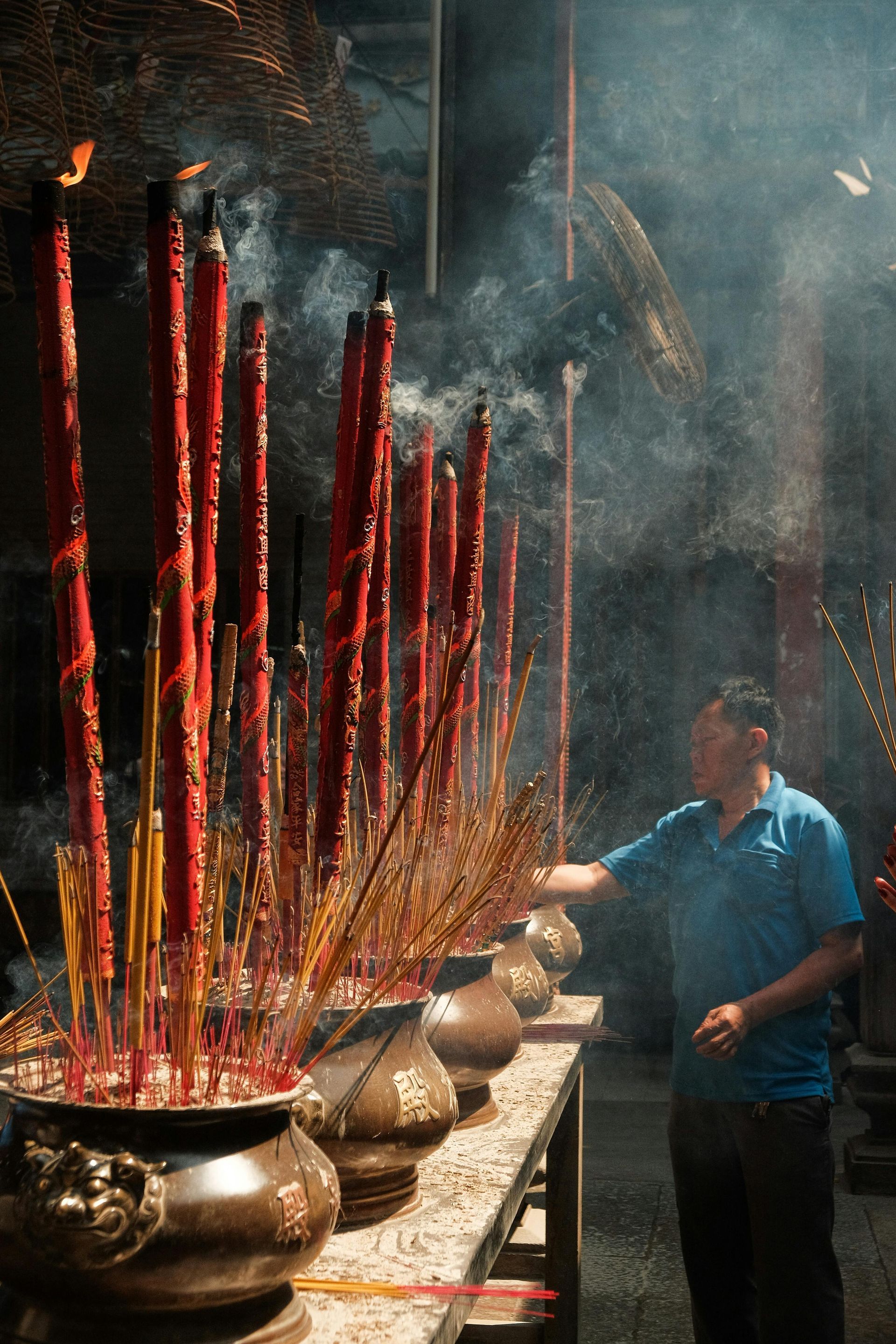 A man is standing in front of a table full of incense sticks in Vietnam.