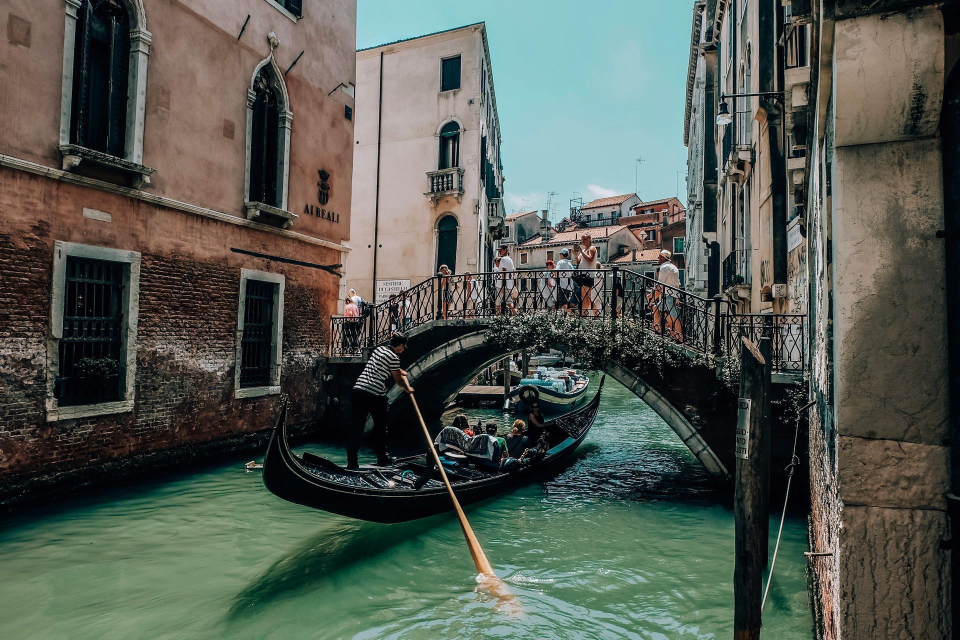 A gondola is going under a bridge in venice.