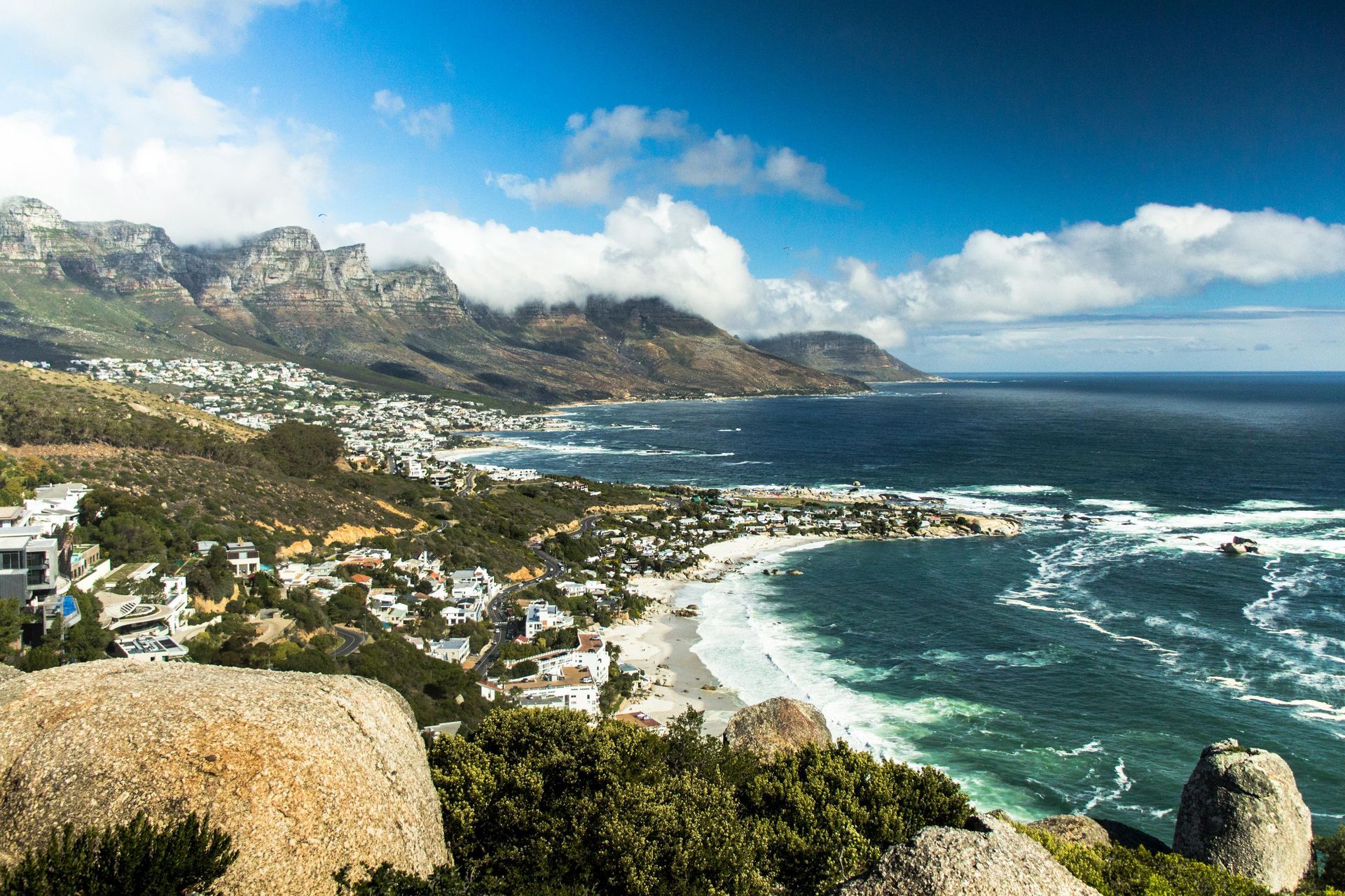 An aerial view of a beach with mountains in the background and a city in the foreground in South Africa.