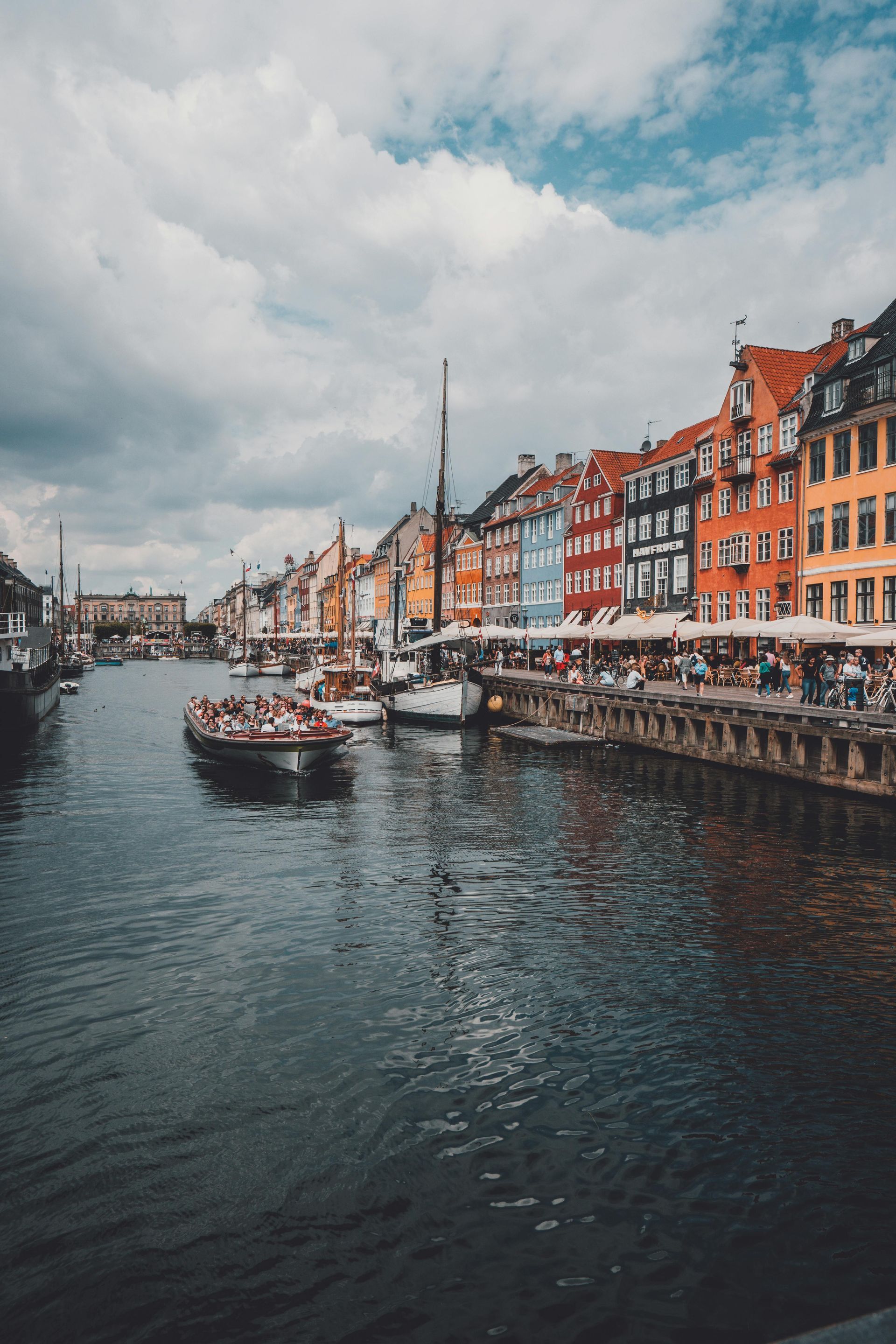 A group of people are riding a boat down a river in a city in Denmark.