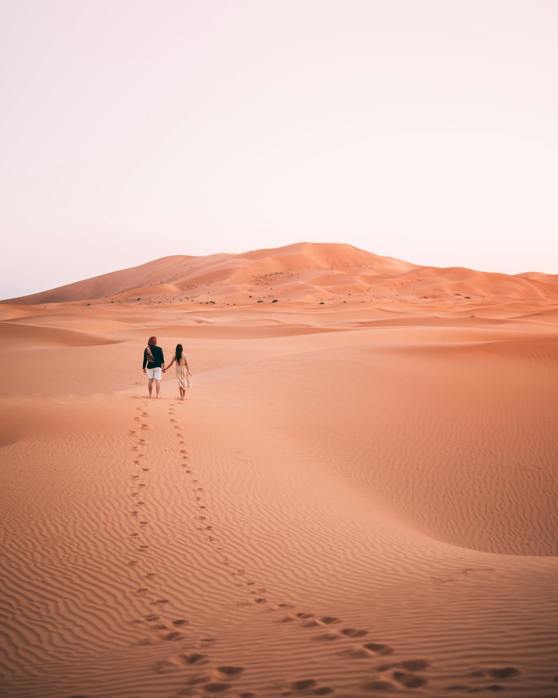 A man and a woman are walking through a desert in Egypt.