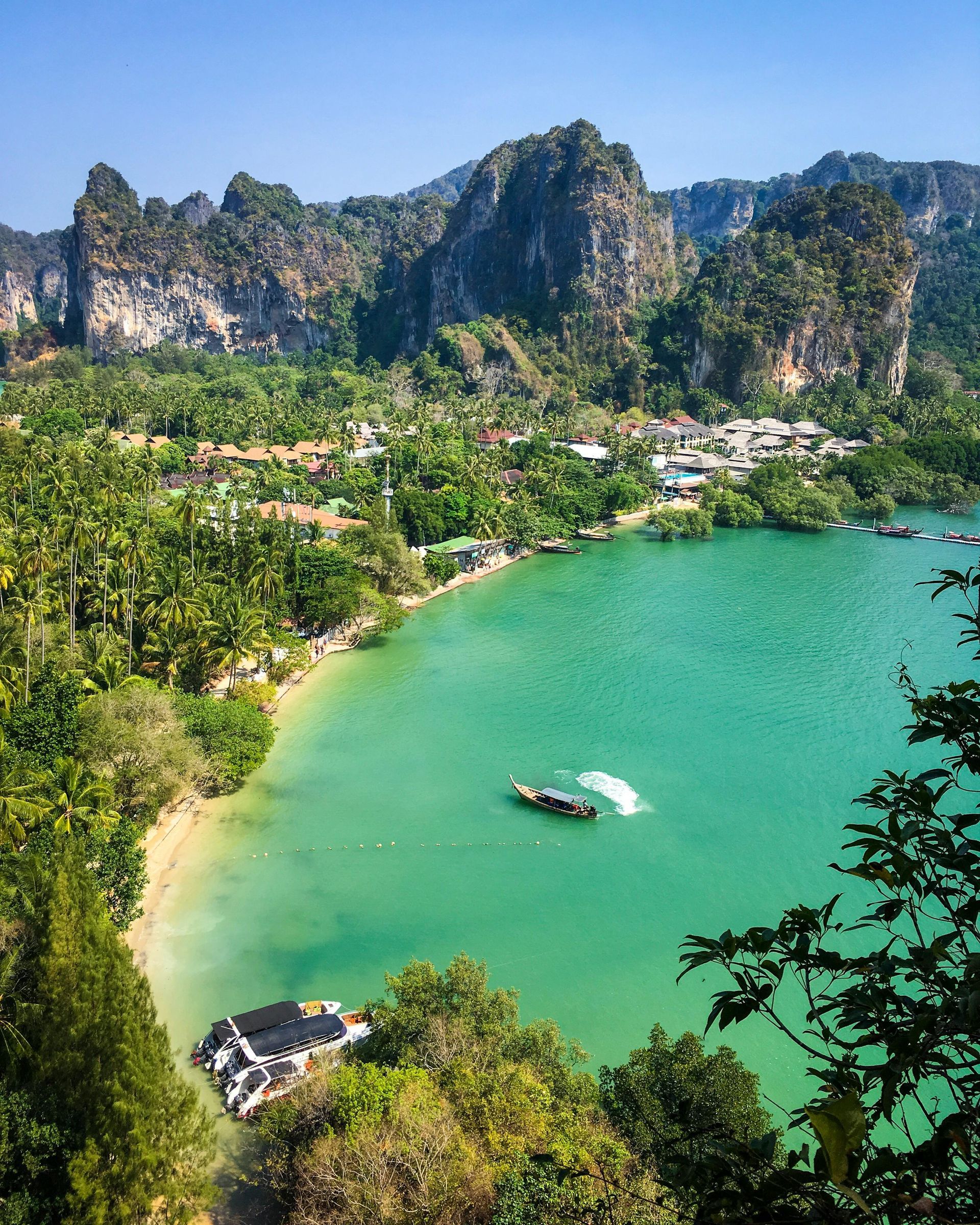 An aerial view of a tropical beach with a boat in the water in Thailand.