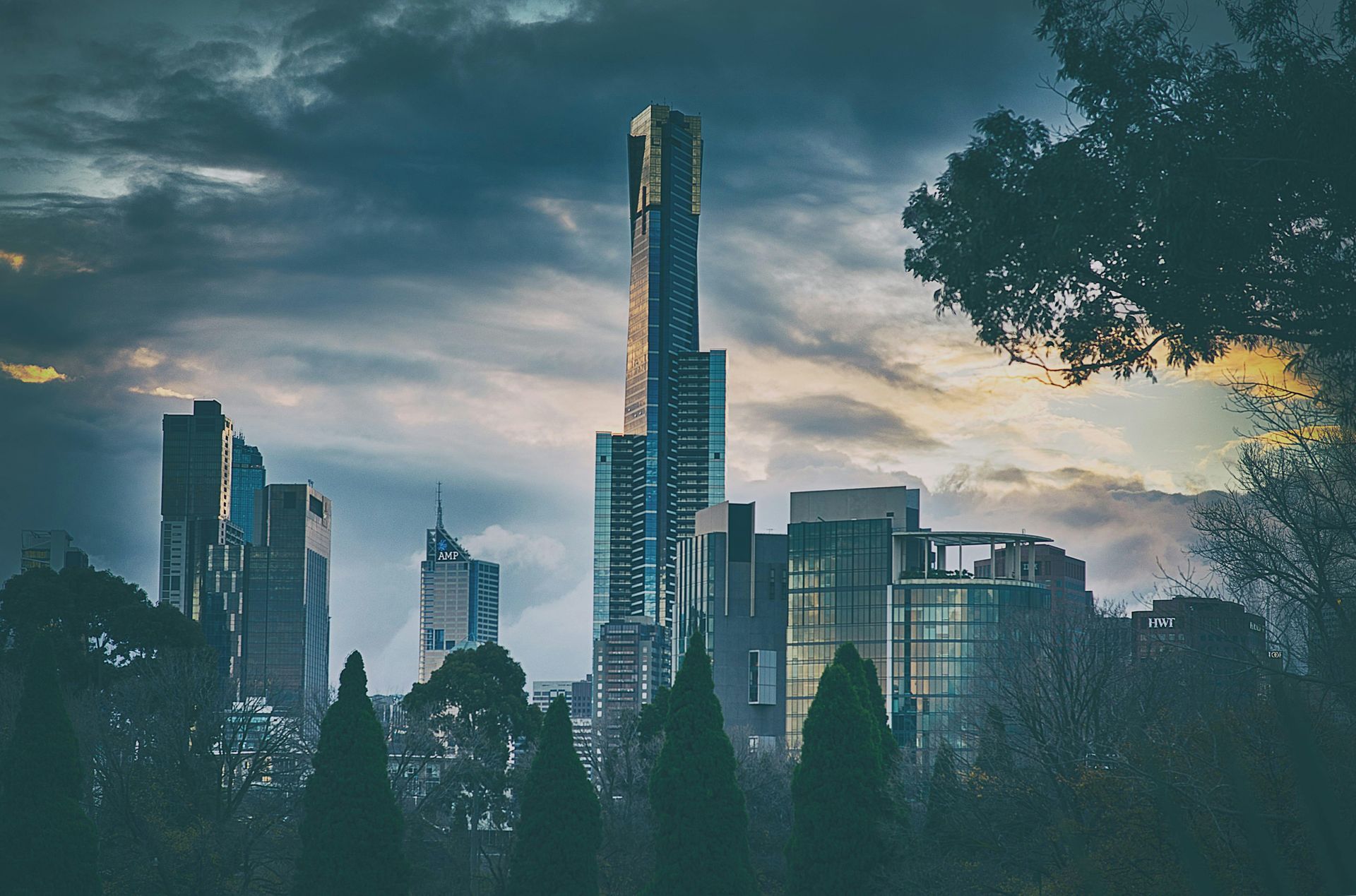 A city skyline with trees in the foreground and a cloudy sky in the background in New Zealand. 