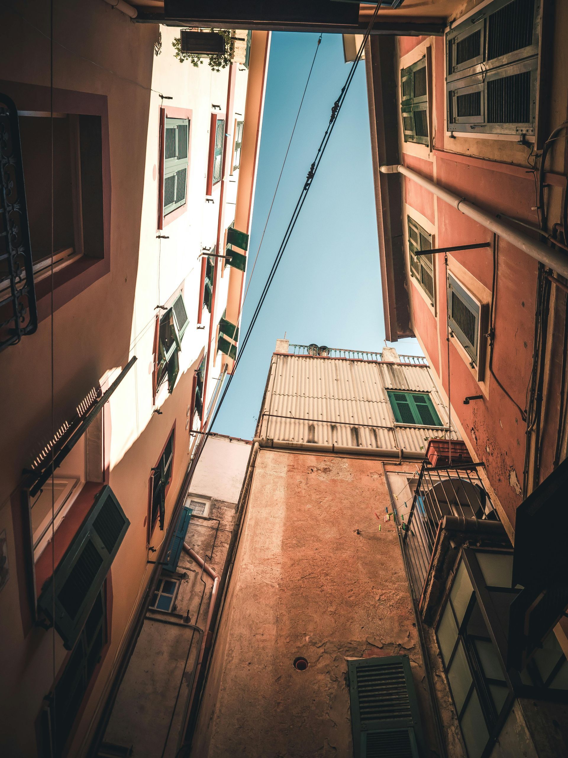 Looking up at a narrow alleyway between two buildings in Cinque Terre, Italy