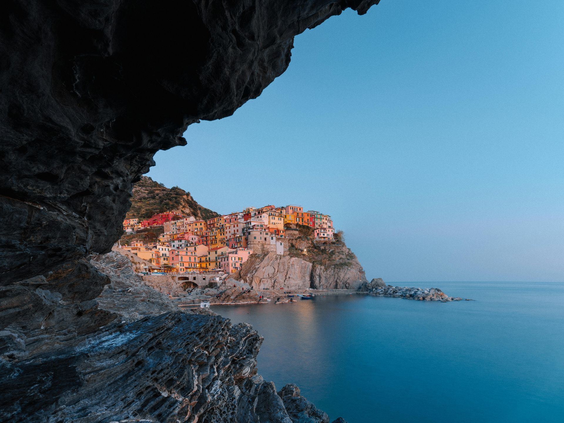 A view of Cinque Terre on a cliff overlooking the ocean from a cave in Italy.