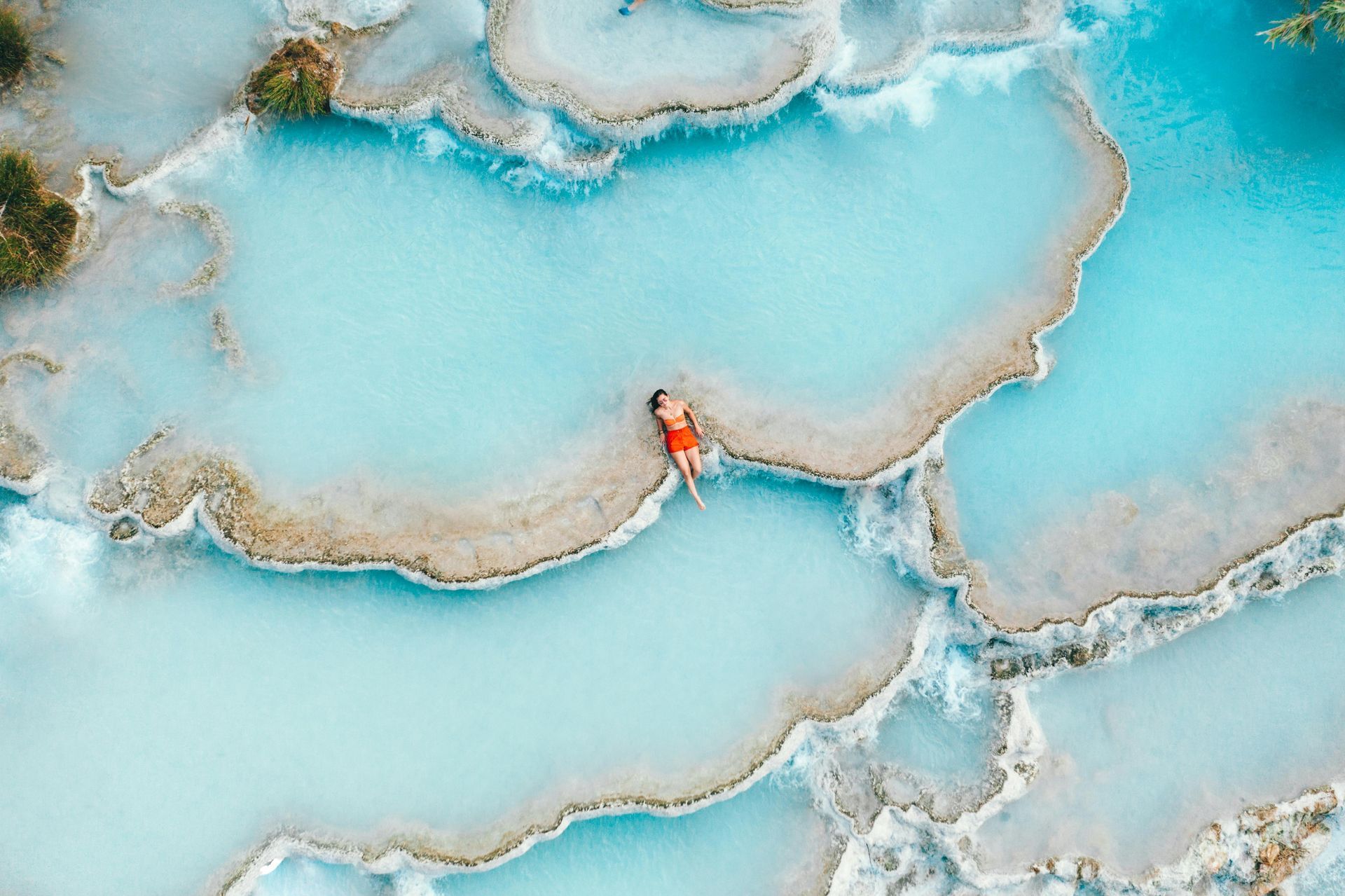 An aerial view of a person laying in the Saturnia Hot Springs in Tuscany, Italy.