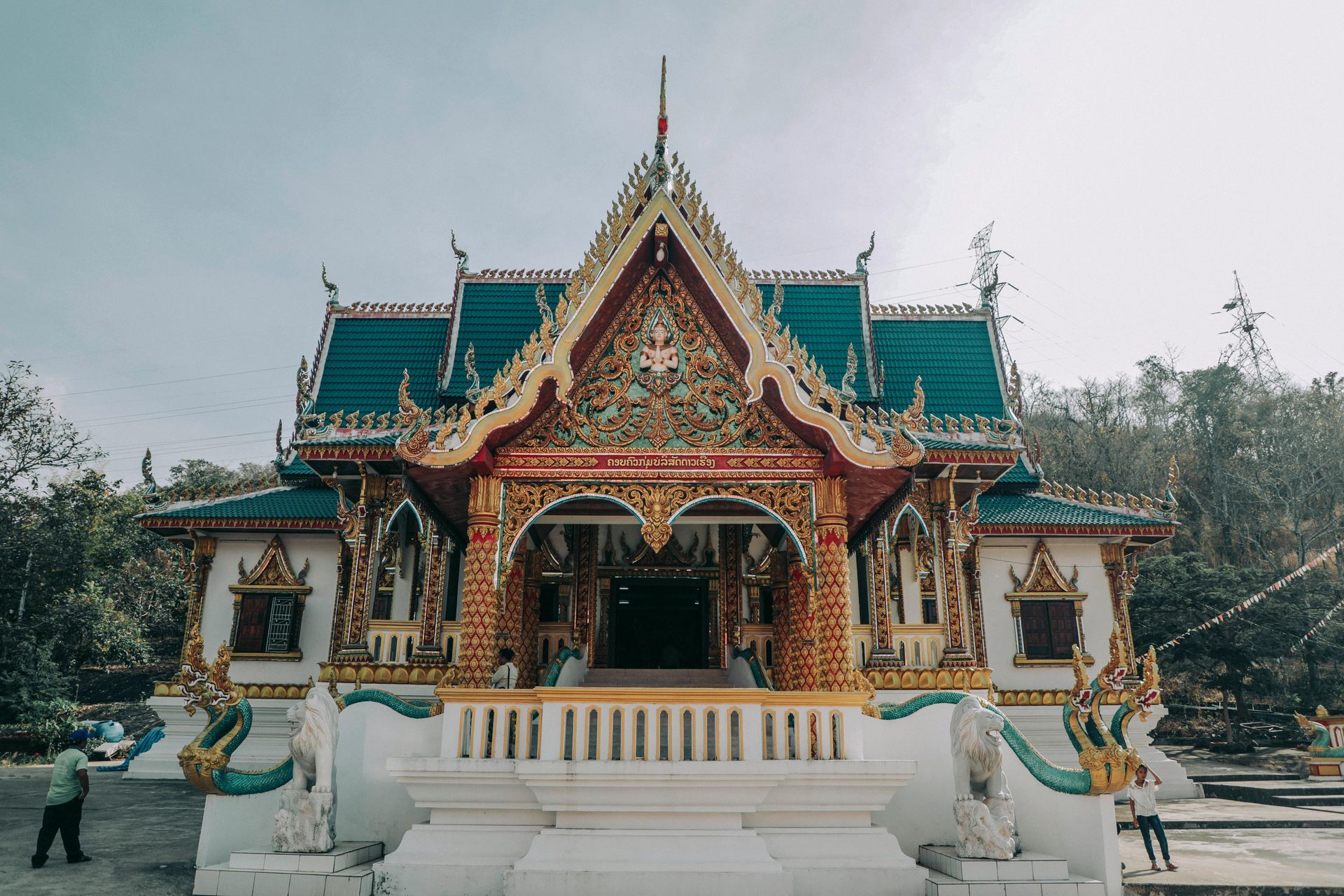 A large temple with a blue roof is surrounded by trees in Laos.