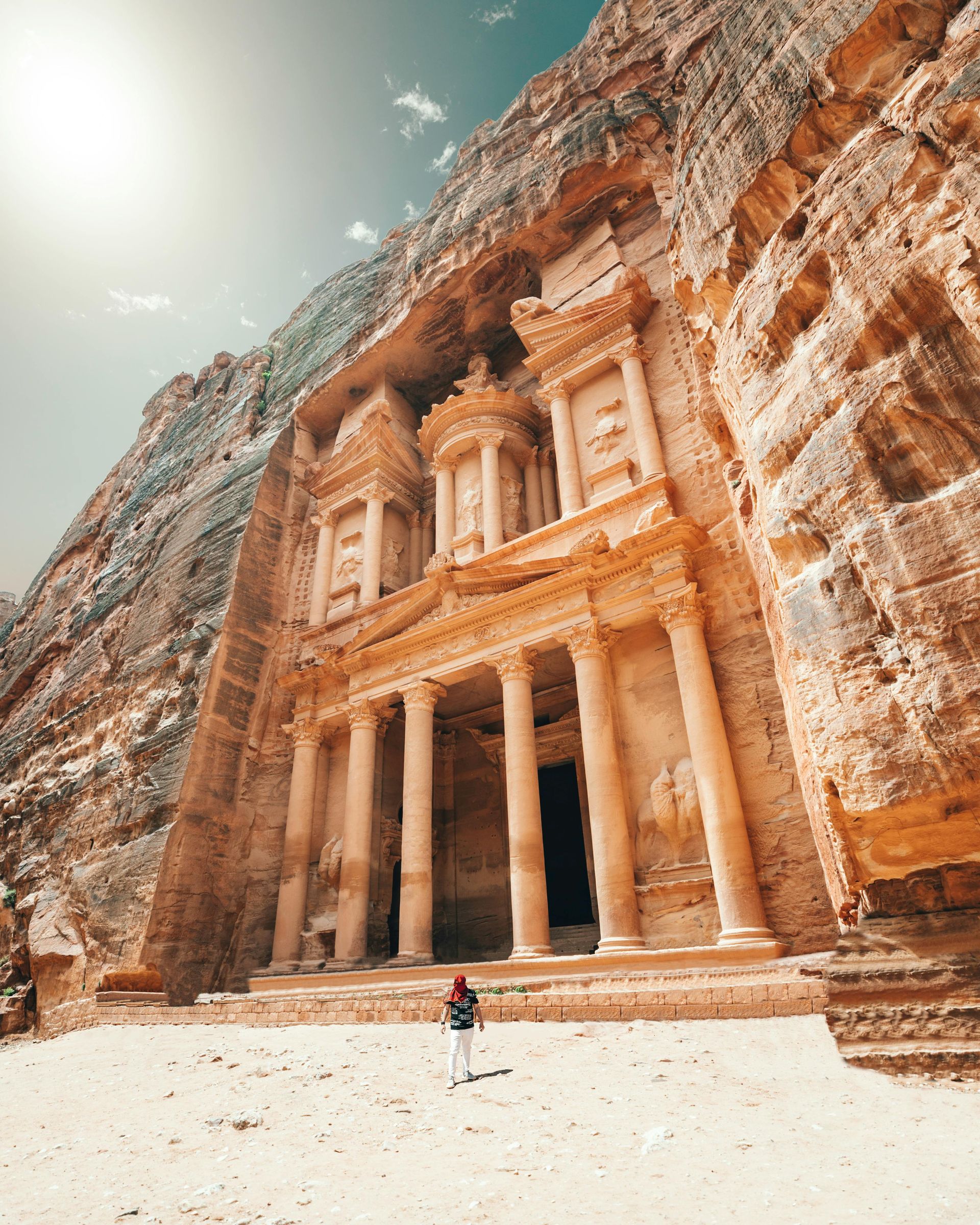 A man is standing in front of the Treasury building in Petra, Jordan.