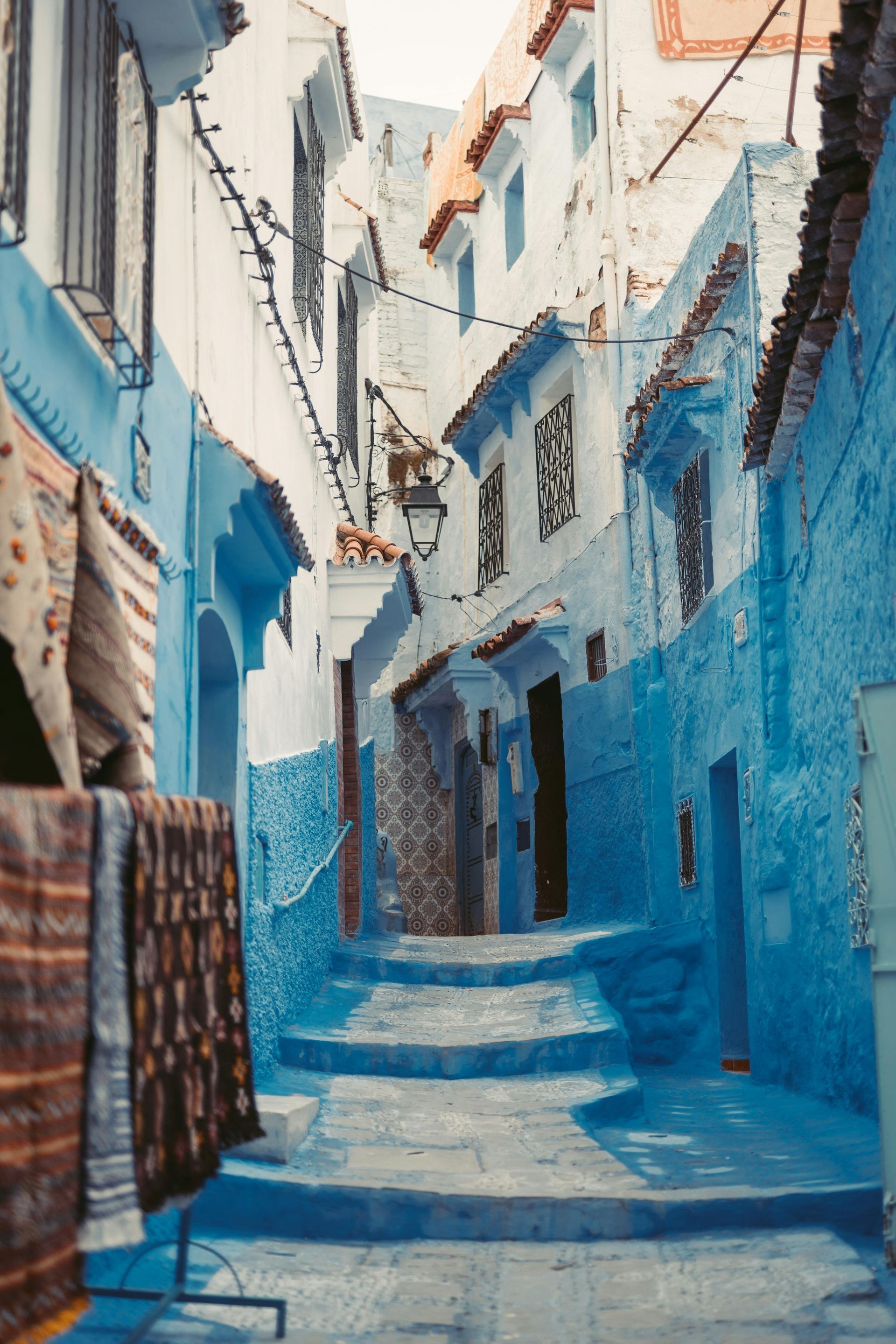 A narrow alleyway with blue steps between two buildings in Morocco.