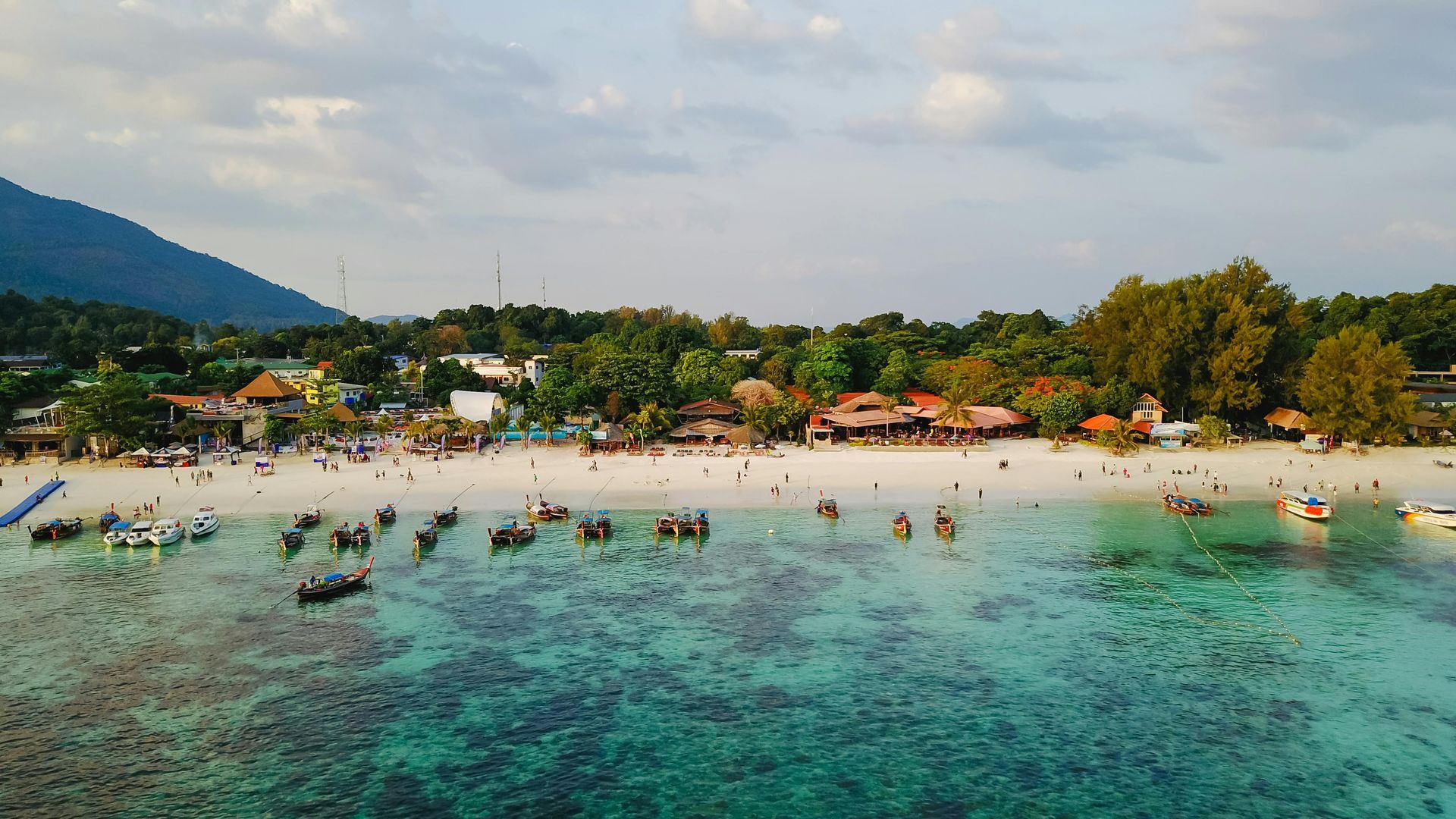 An aerial view of a beach with boats in the water in Thailand.