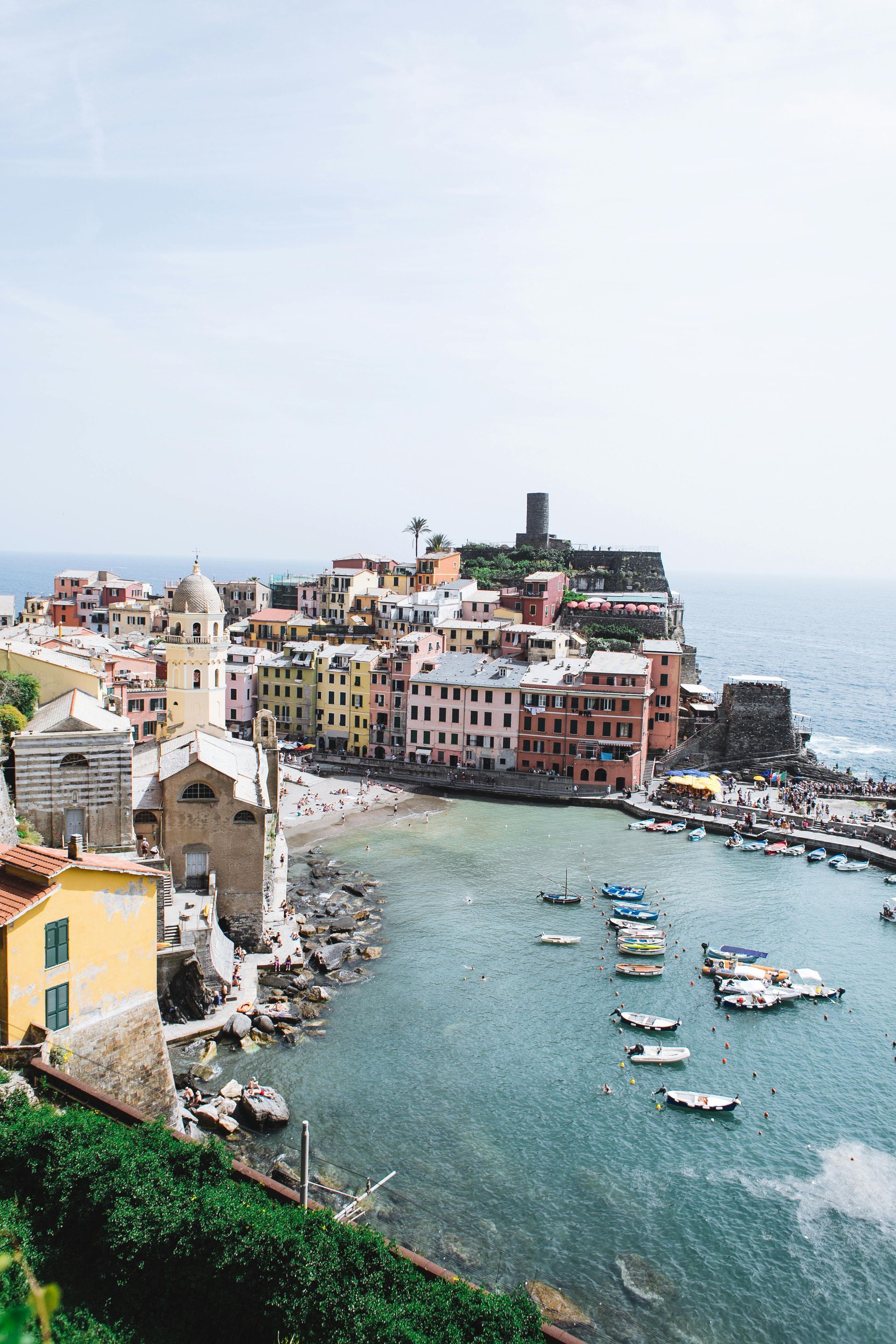 An aerial view of Cinque Terre next to the ocean with boats in the water in Italy.